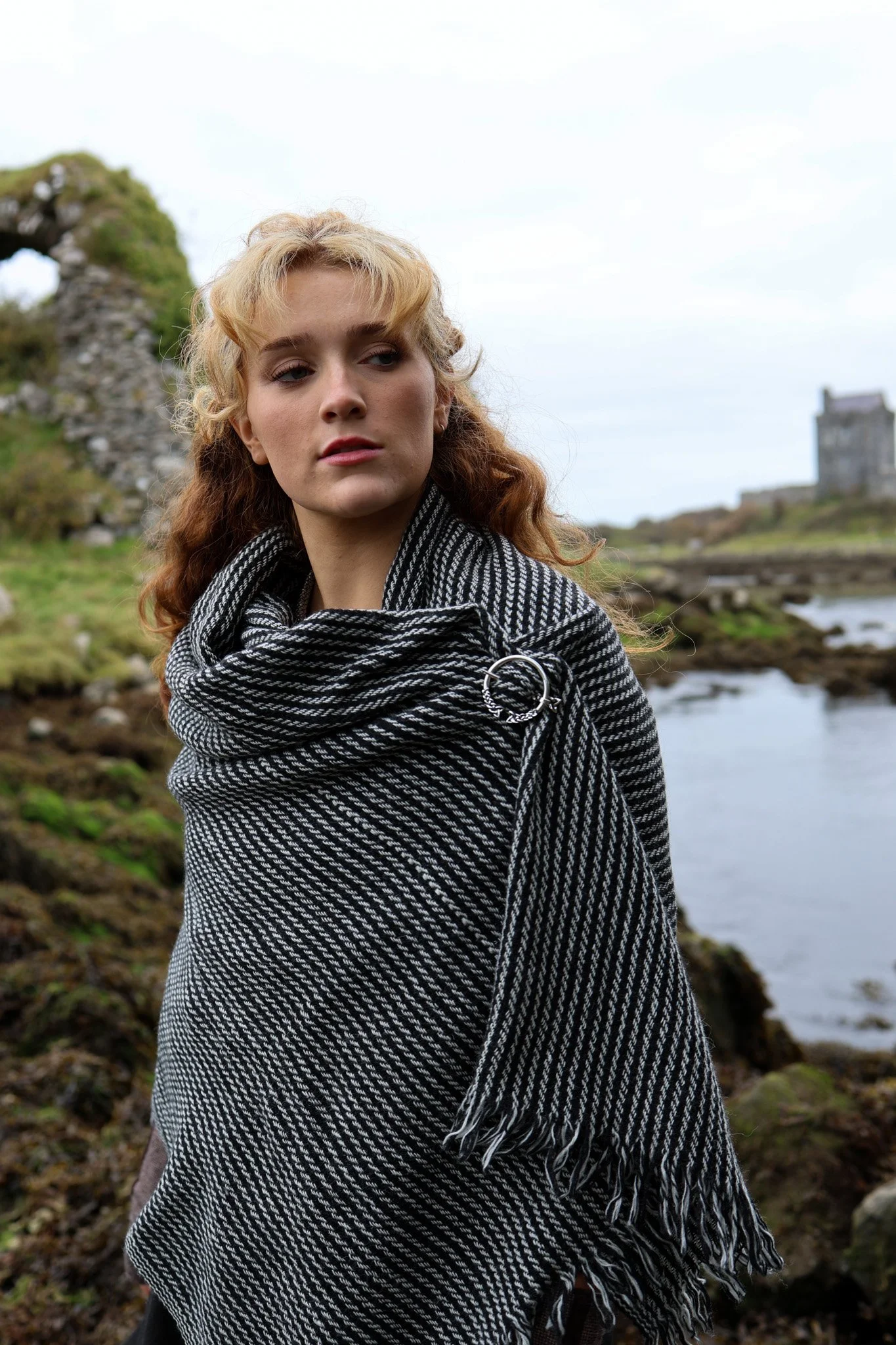 Model wearing a handwoven black and grey Celtic shawl secured with a silver-plated Trinity Knot brooch by Celtic Fusion Design. Photographed in the Irish countryside