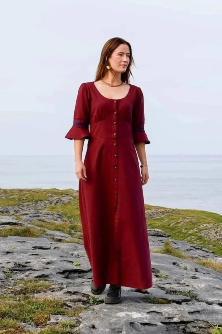 Model wearing a deep berry red Celtic dress with Celtic knot embroidery, button-down front, and flowing sleeves – Pooka Hawthorn Dress by Celtic Fusion Design