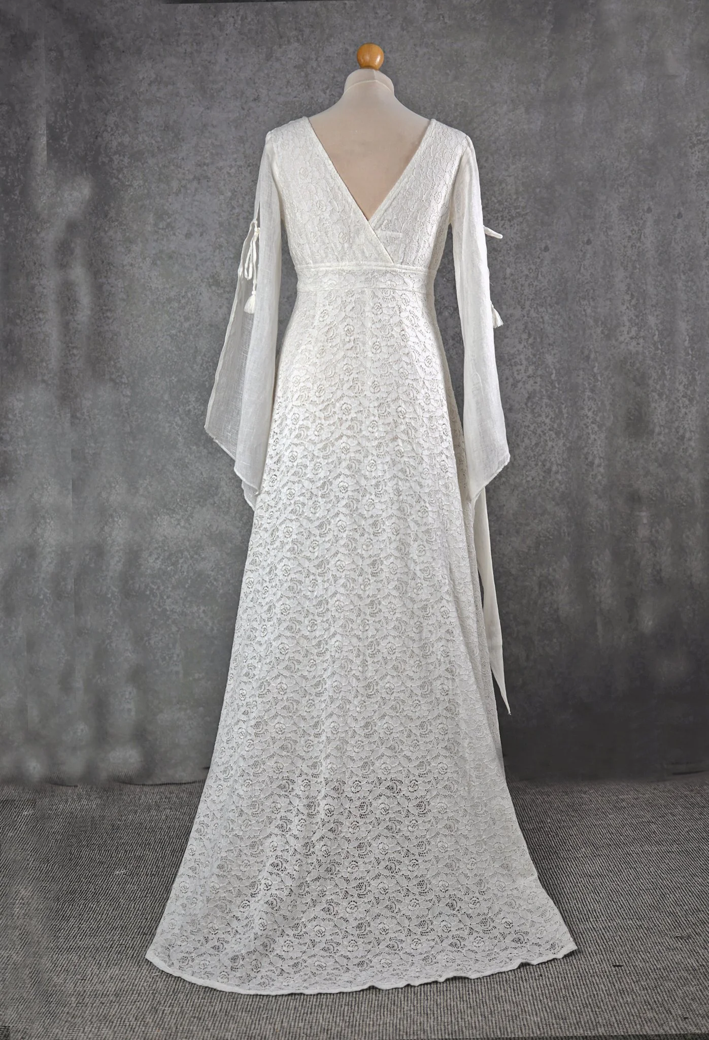 The Ava Wedding Dress is a romantic lace gown with linen net sleeves, tie details, and an A-line silhouette. Ethically made from deadstock fabrics in Ireland.