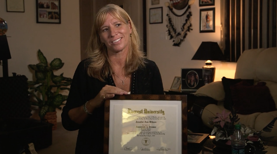 Fail State Student Jennifer Wilson holding her "worthless" diploma from now-defunct Everest University.