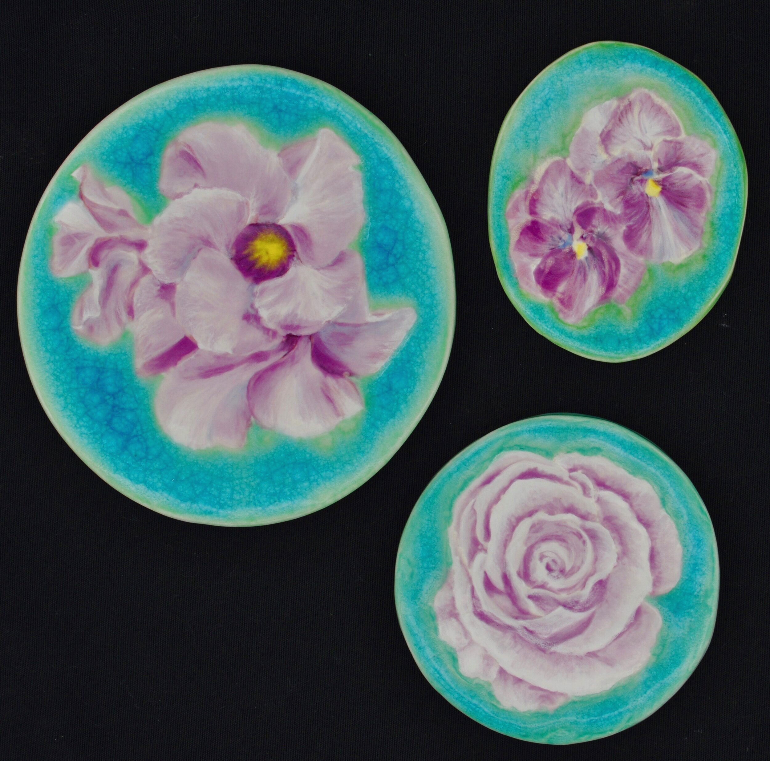  Clockwise from left:  1) Mandevilla - 7.5” tall oval tile ($40)  2) Pansies - 5.25” tall oval tile ($25)  3) Single Rose - 5.5” diameter round tile ($40)   