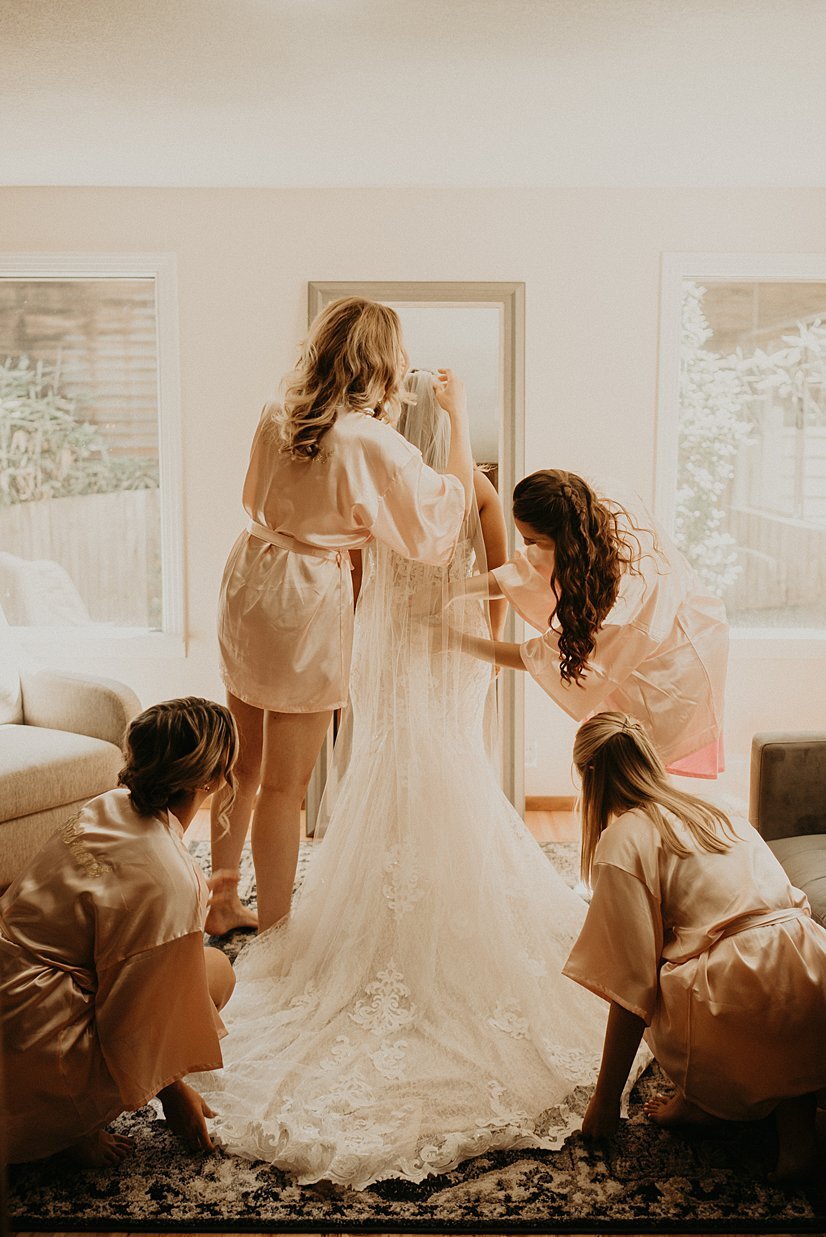  bridesmaids assisting bride getting dressed for backyard wedding near Seattle 