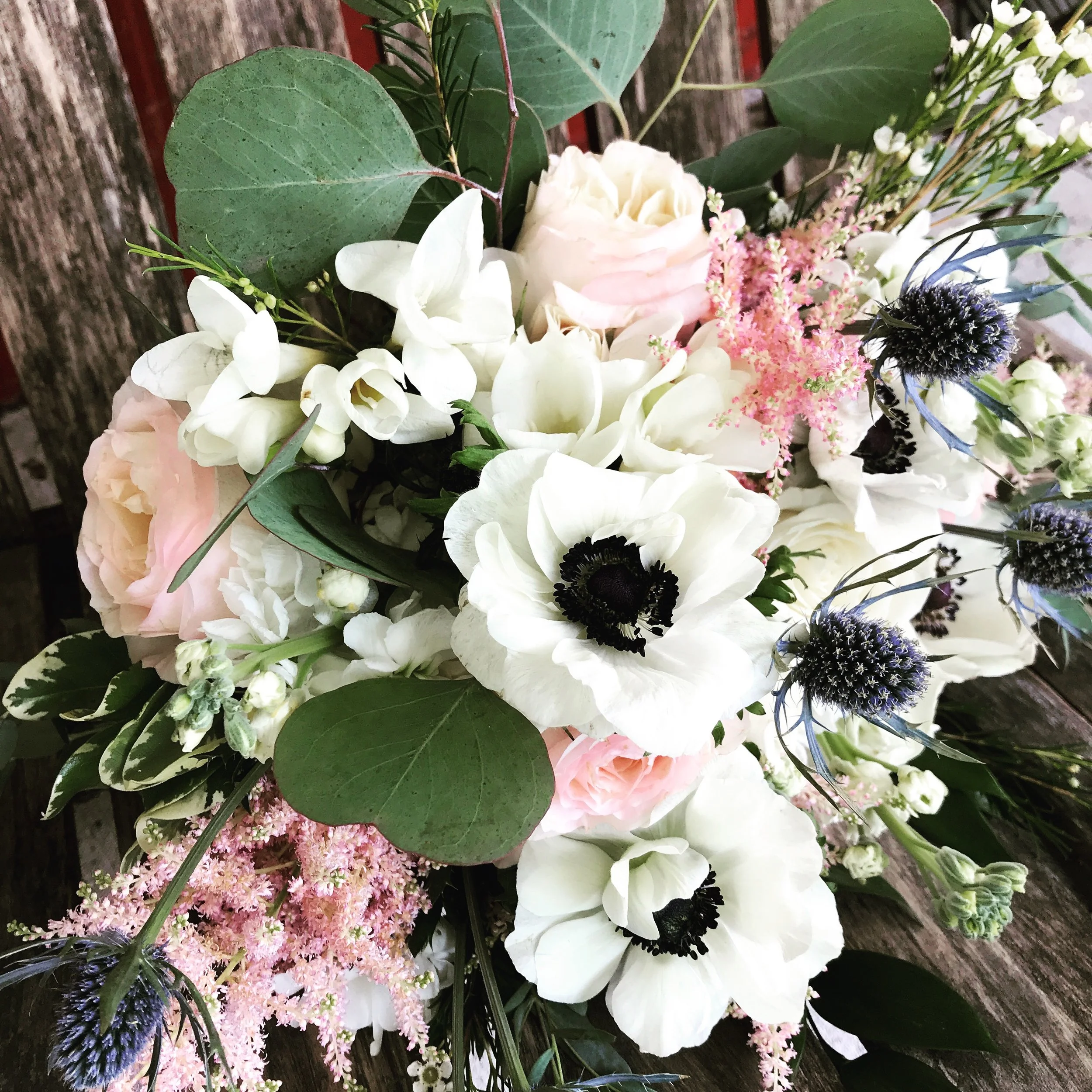 White anemones with blush roses and blue thistle
