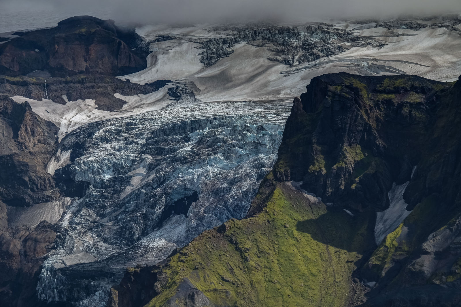 Glacial ice contrasting with the rock of the mountains and the green moss and grass, Þórsmörk
