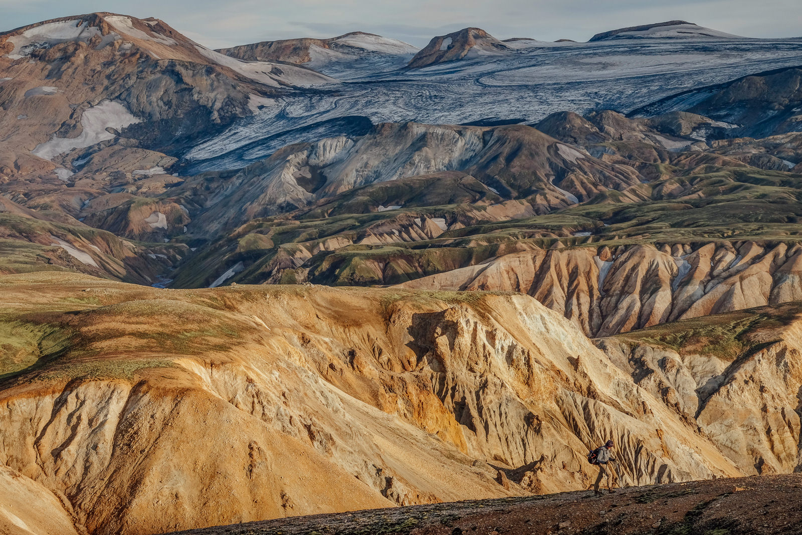A fellow hiker walks on the backdrop of Landmannalaugar Highlands, Iceland - one of the most beautiful places to travel to and have a hike among spectacular landscapes.