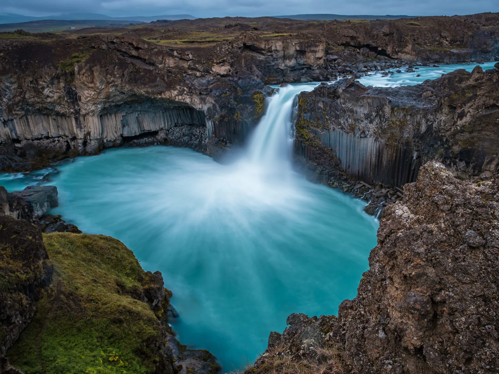 Water streams form beautiful patina on the basalt column framed basin bellow the Aldeyjarfoss waterfall on a rainy and windy day. Long(ish) exposure and filters made the colours pop though. The waterfall, about 20m tall, is one of the most beautiful in Iceland (XF 16-55mm f2.8 at 16mm 15s f8 ISO100)