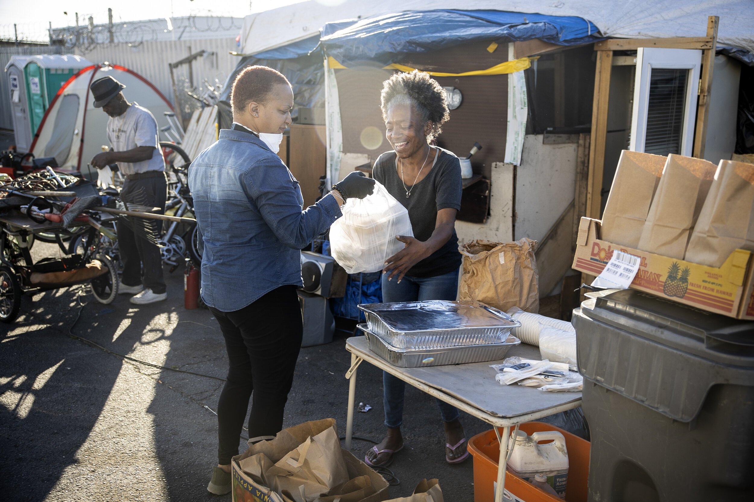  Candice Elder delivers food from Lena's Soul Food Cafe and Aburaya to unhoused residents of East Oakland at the 77th Ave. homeless encampment in Oakland, Ca. Martin do Nascimento / Social Care Stories 