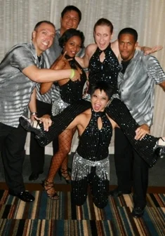Six dancers posing for the camera, wearing black and white costumes