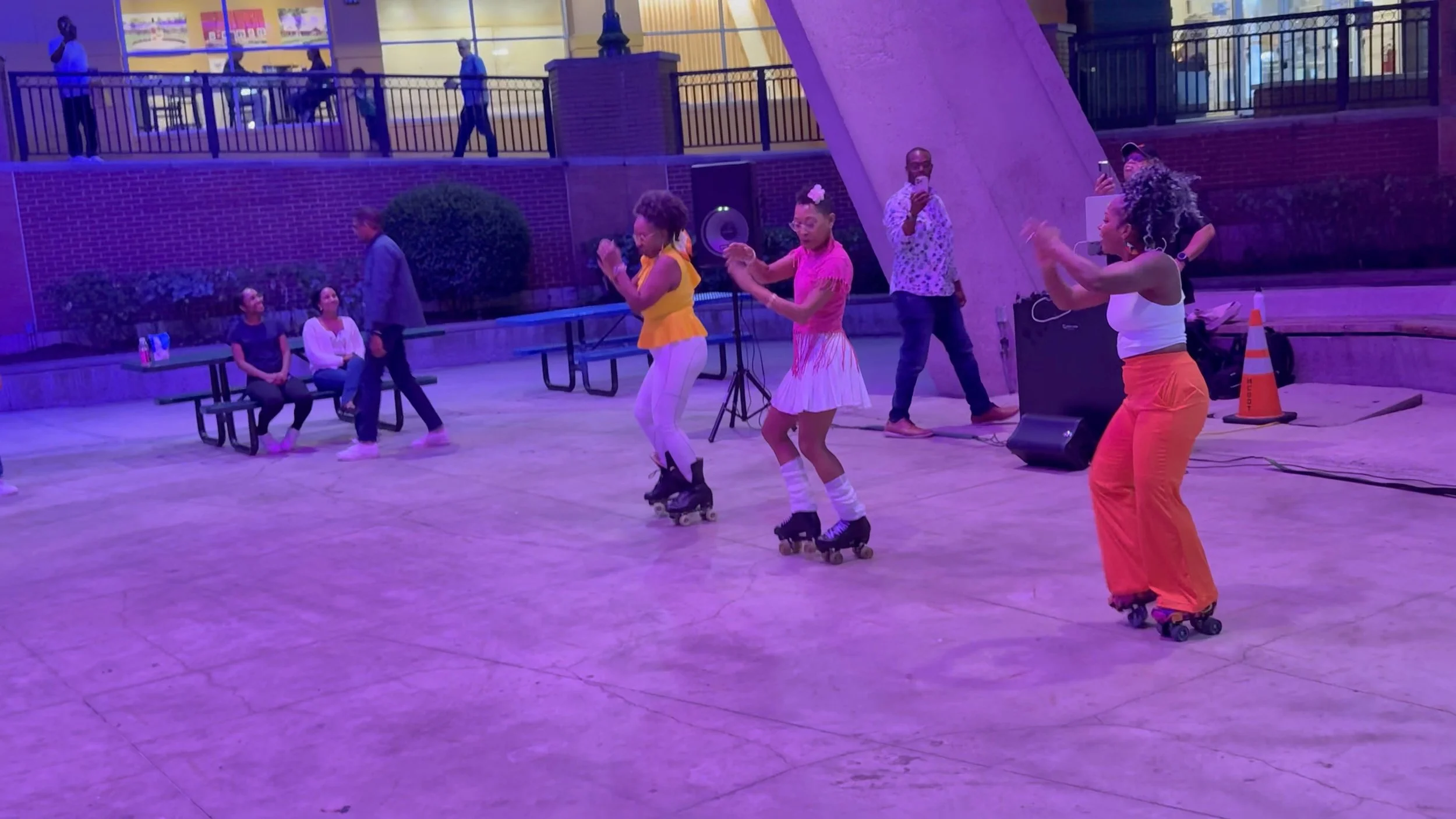 Three women dancing on rollarskates at an outdoor venue
