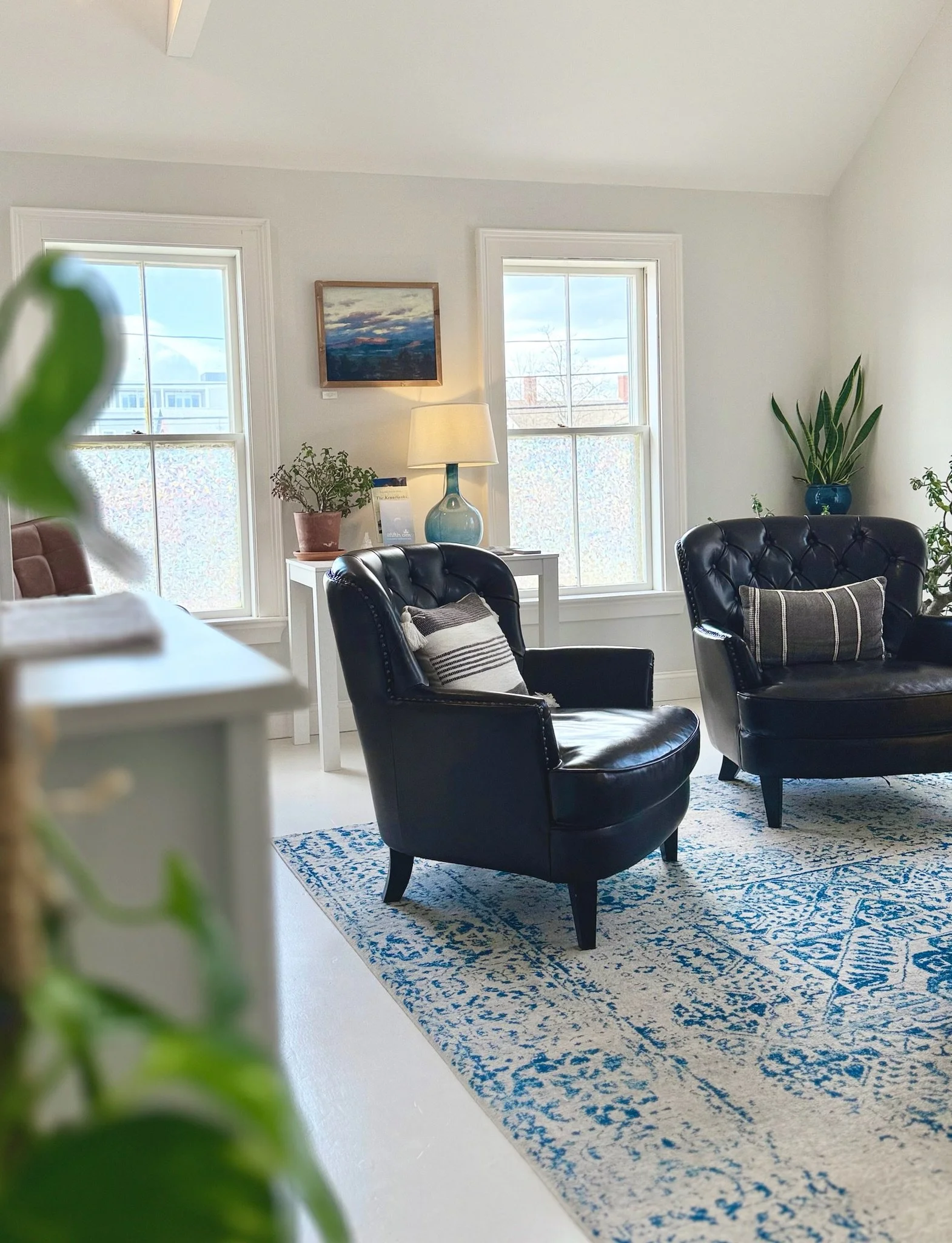 Bright and calming wellness spa lounge with leather chairs, natural light, plants, and coastal-inspired decor at The Fifth Om in Kennebunk, Maine.