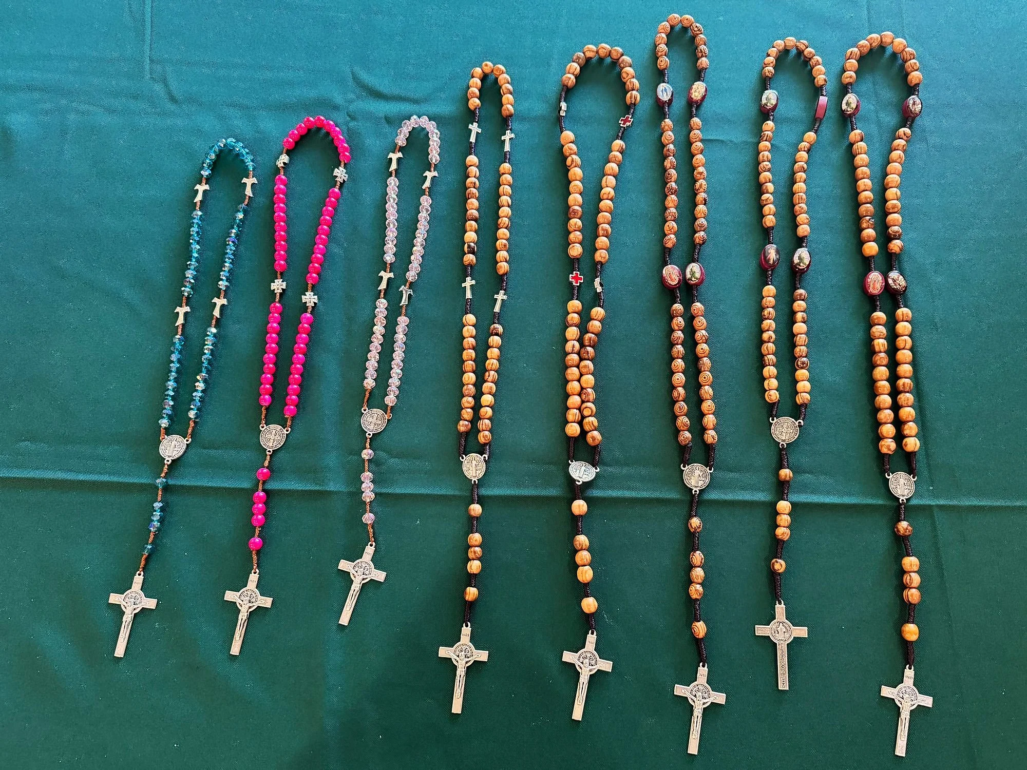 Olive-wood and crystal rosaries with St. Benedict crucifixes on the parish table