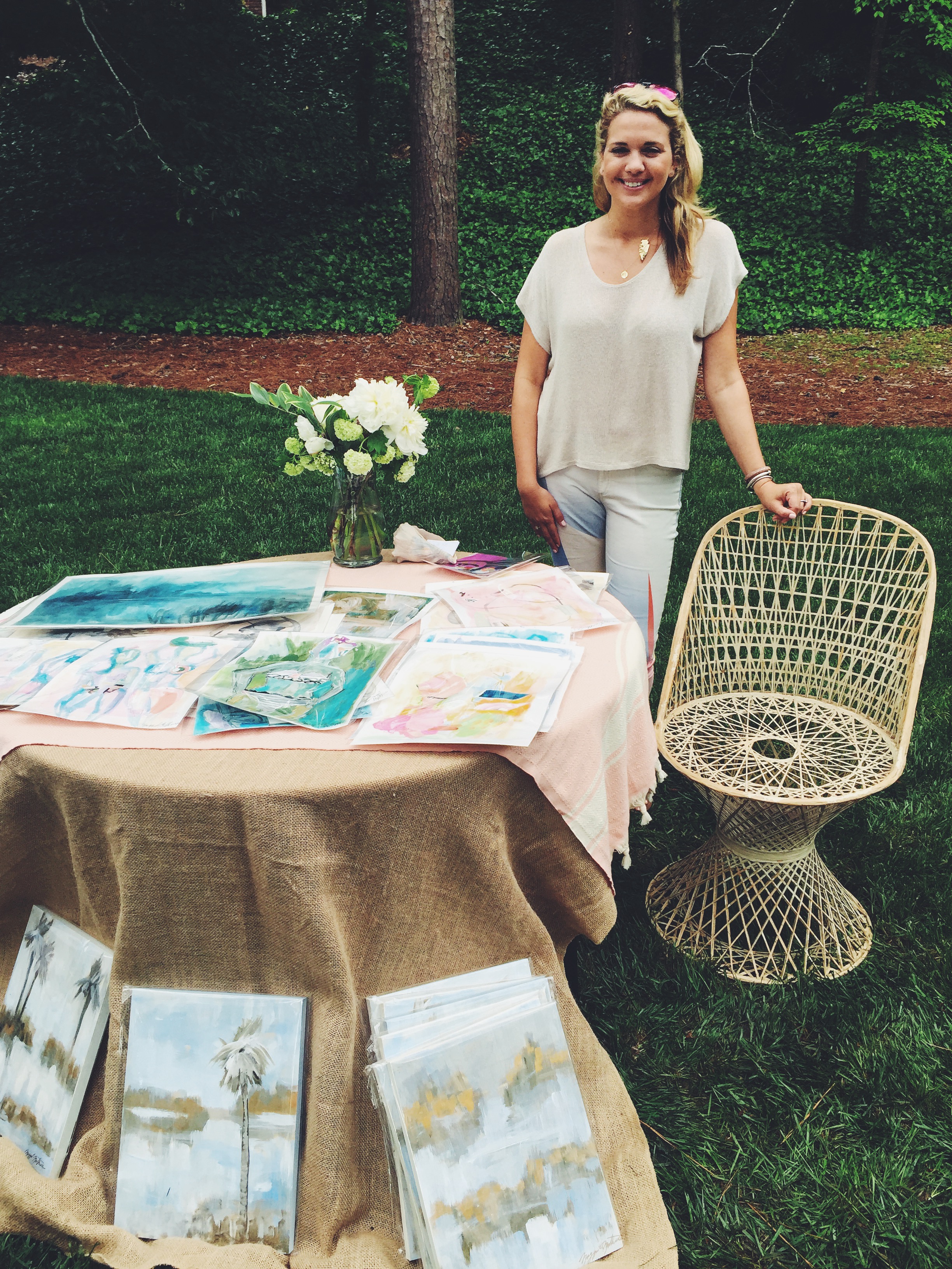 Maggie Mathews standing with her beautiful works and the best chair at the show. 