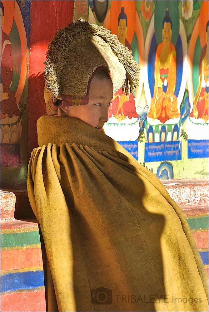 Novice monk in yellow robe and headwear in the cloisters at Tashilunpo monastery, Shigatse,Tibet. (License this Image)