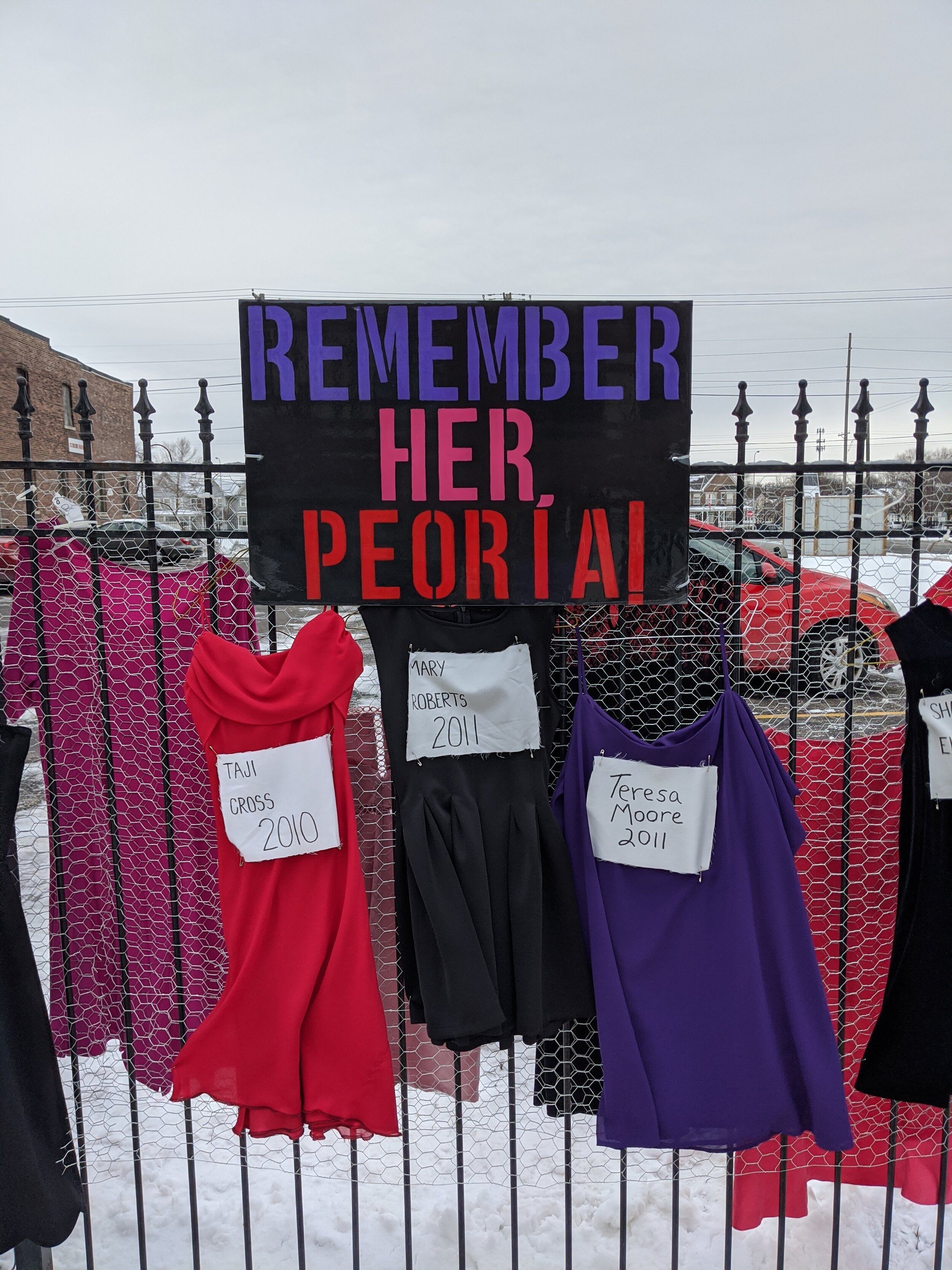   Remember Her, Peoria!   Collaborative Public Installation honoring the missing and murdered women of Peoria from 1993-2019  Dresses, fabric, fabric markers, hangers  2020   In collaboration with community leaders and activists:    Susan O’Neal    N