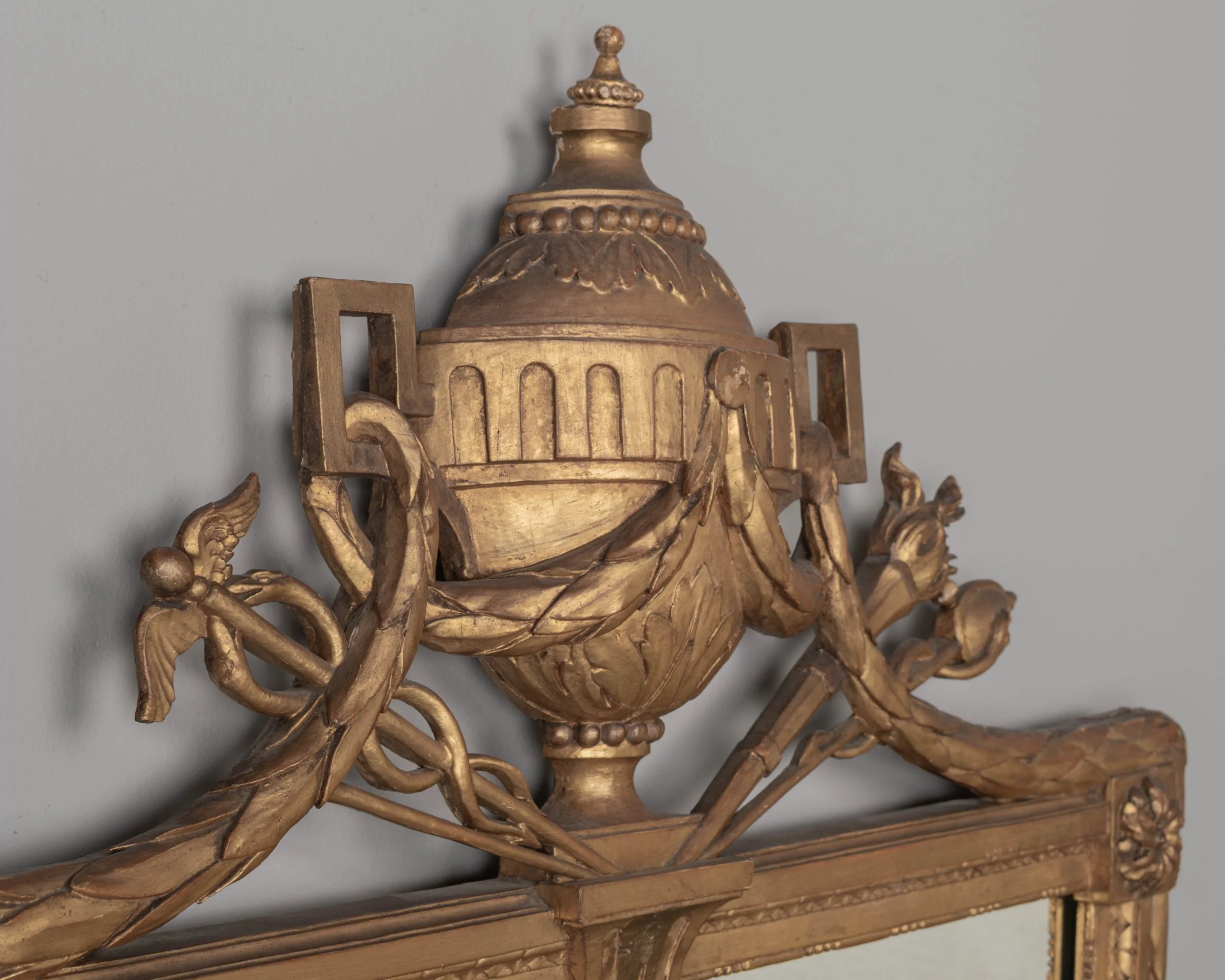 A Louis XVI style French giltwood mirror. Hand carved crest with large urn, torch, ribbons, and garlands.