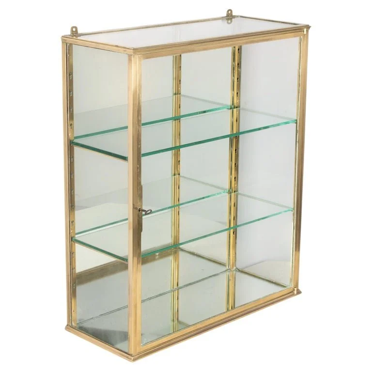A French Art Deco hanging wall vitrine with solid brass frame, mirrored back and glass panes.