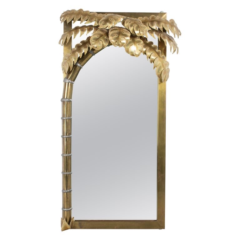 An iconic brass palm tree illuminated wall mirror designed by Christian Techoueyres for Maison Jansen. Crafted of brass sheet metal over wood with a canopy of torch cut and welded burnished brass palm fronds. The metal is in good condition, with a ni