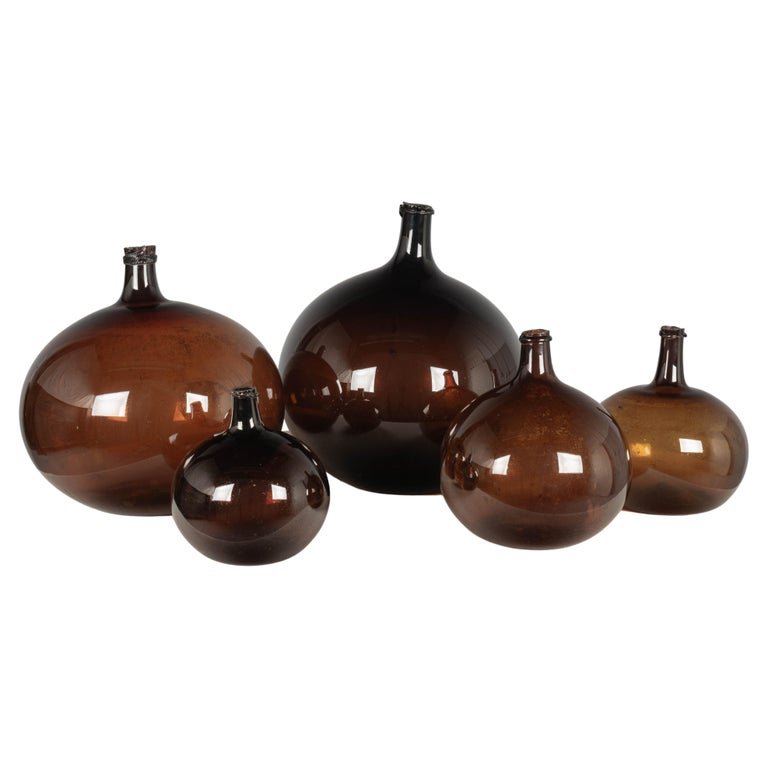 A set of five 19th century French globular form amber glass demijohn bottles with air bubbles typical of handblown glass. Circa 1850-1860
