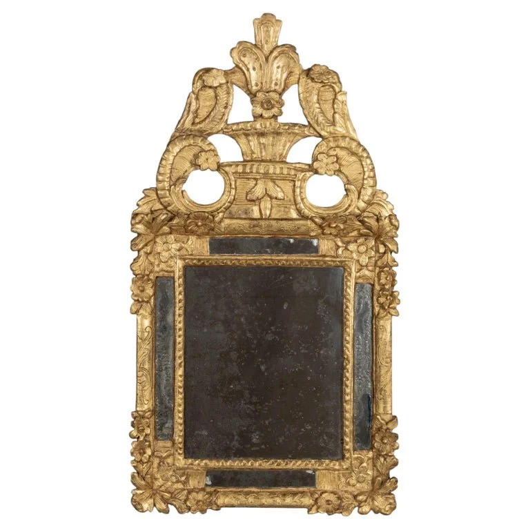 An 18th century French Regence style giltwood parclose mirror with large boldly carved sculptural crest and elaborate floral and leaf form corner decorations