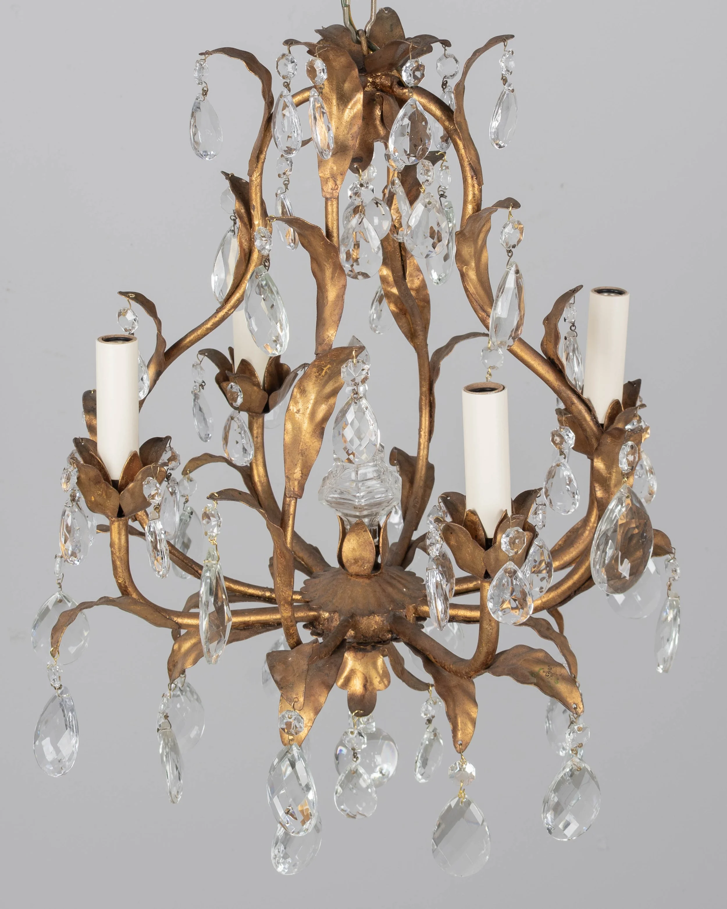 An Italian Hollywood Regency style four-light gilt metal chandelier with tôle leaves and crystal prisms.