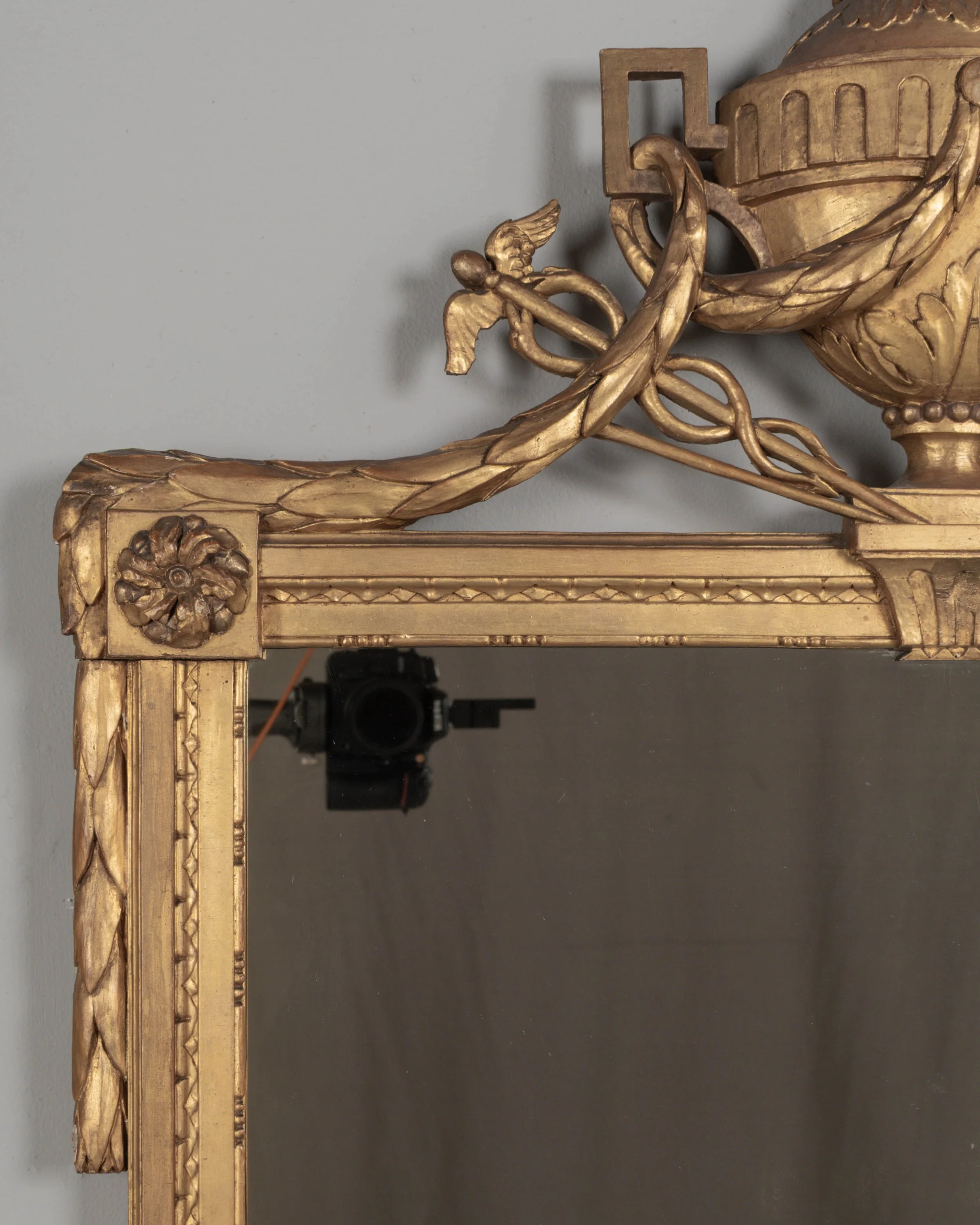 A Louis XVI style French giltwood mirror. Hand carved crest with large urn, torch, ribbons, and garlands.