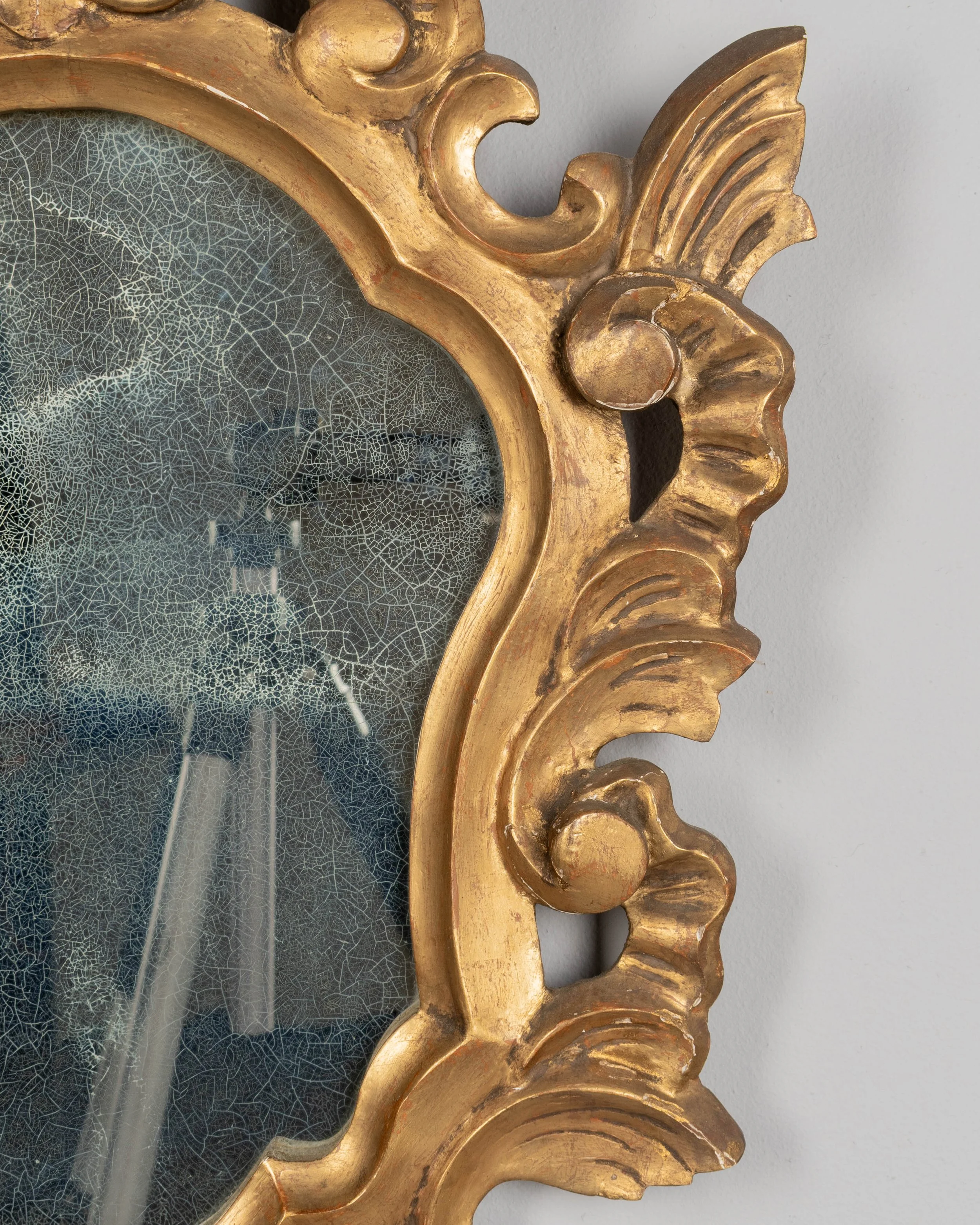 French Baroque style giltwood mirror with cartouche shape framed by undulating borders.
