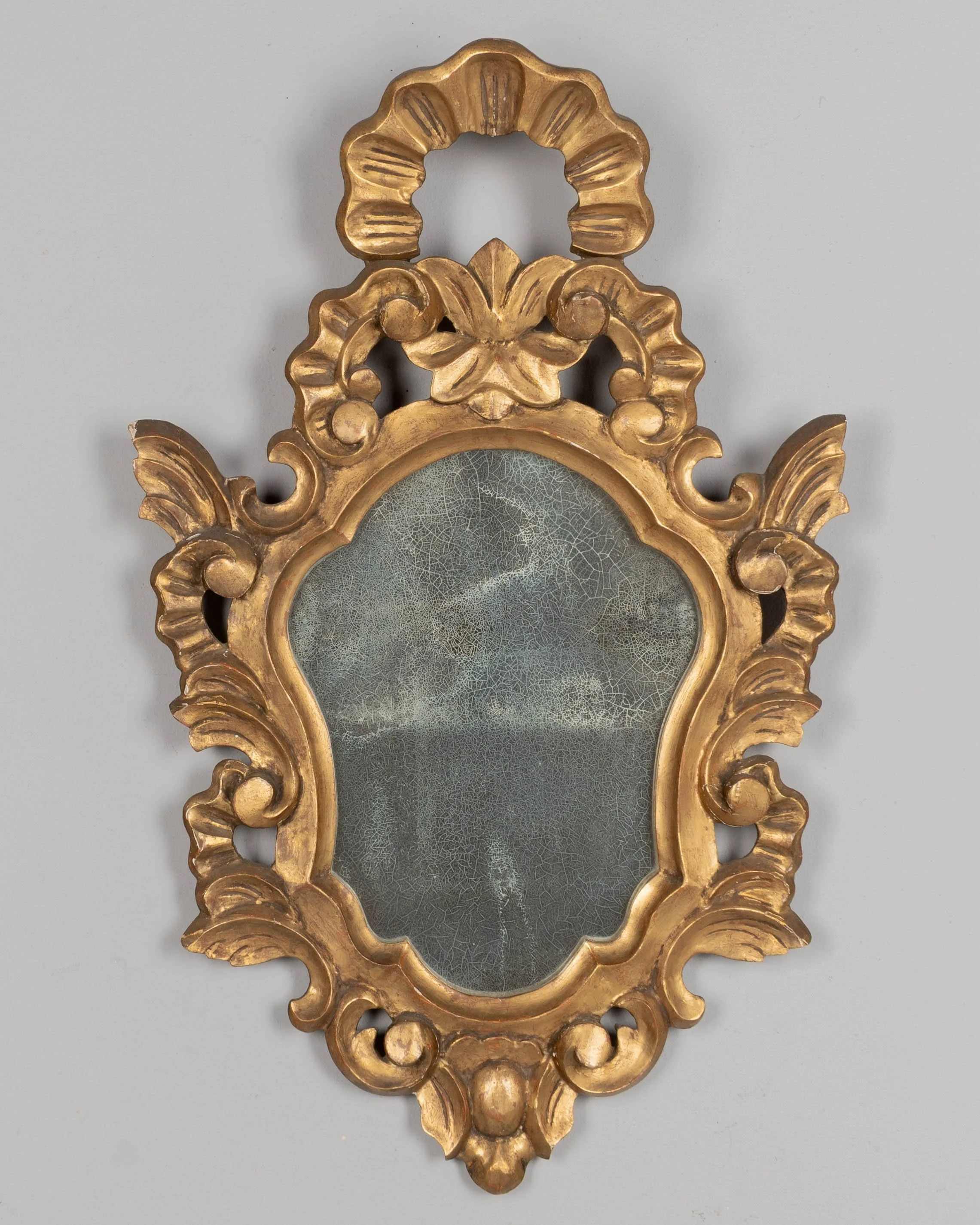 French Baroque style giltwood mirror with cartouche shape framed by undulating borders.