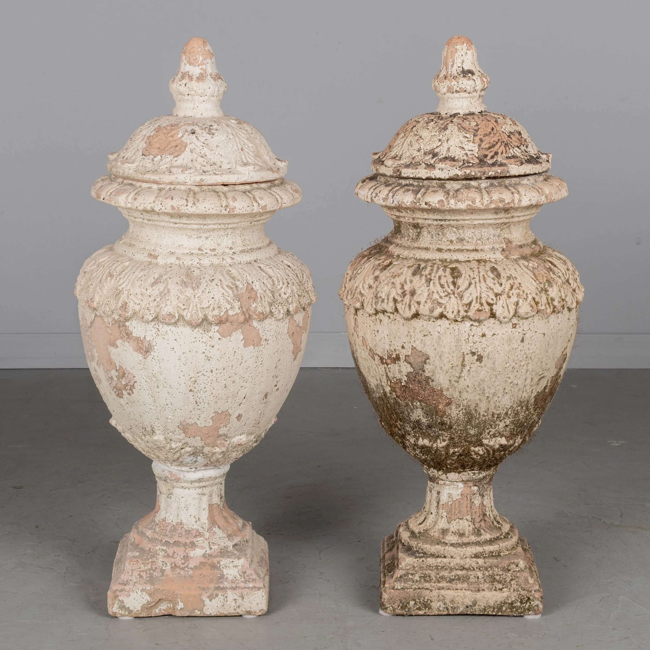 A pair of French terracotta garden urns with lids. Classical vase form on pedestal base, decorated in acanthus leaf motif with large acorn finials on lids.