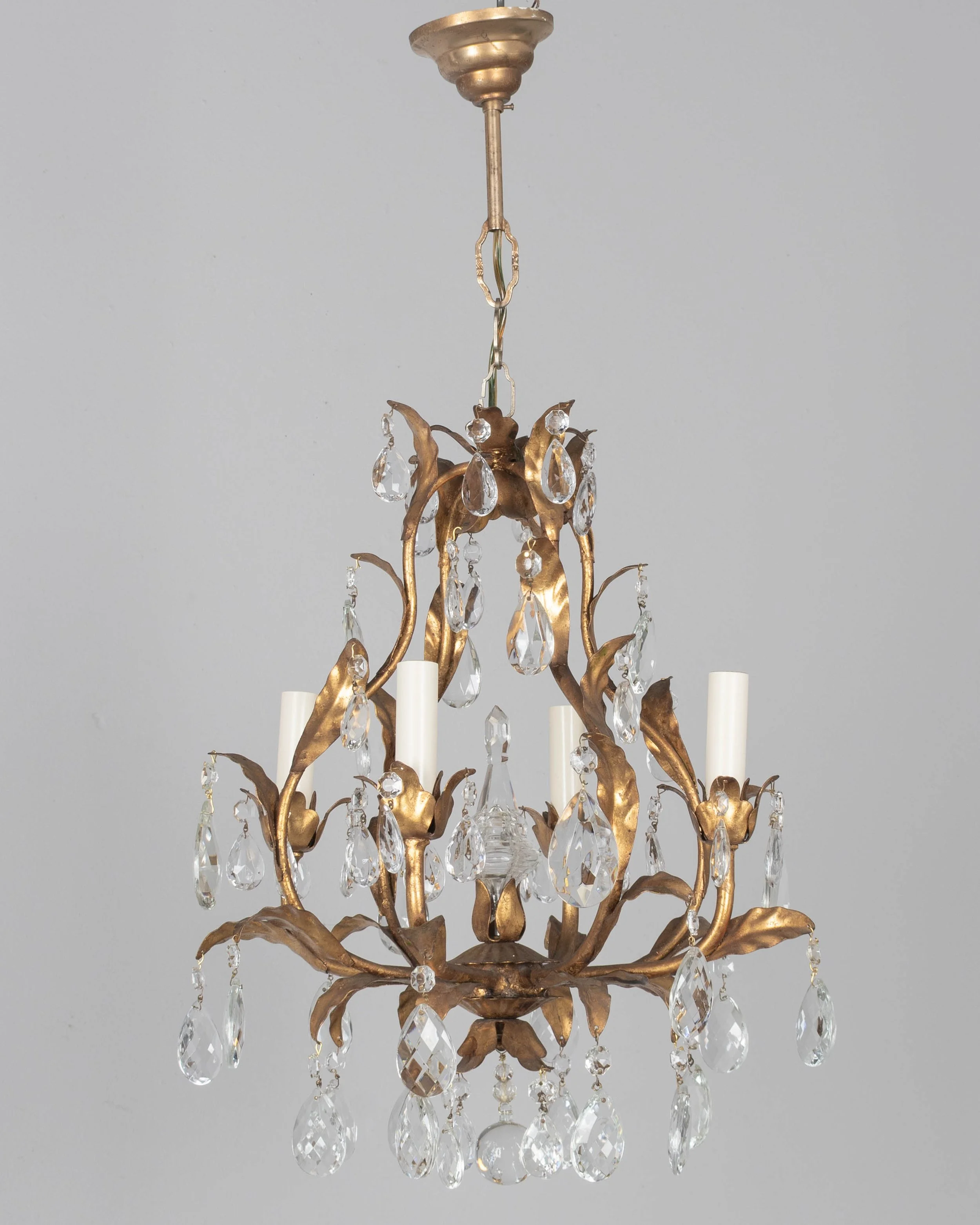 An Italian Hollywood Regency style four-light gilt metal chandelier with tôle leaves and crystal prisms.