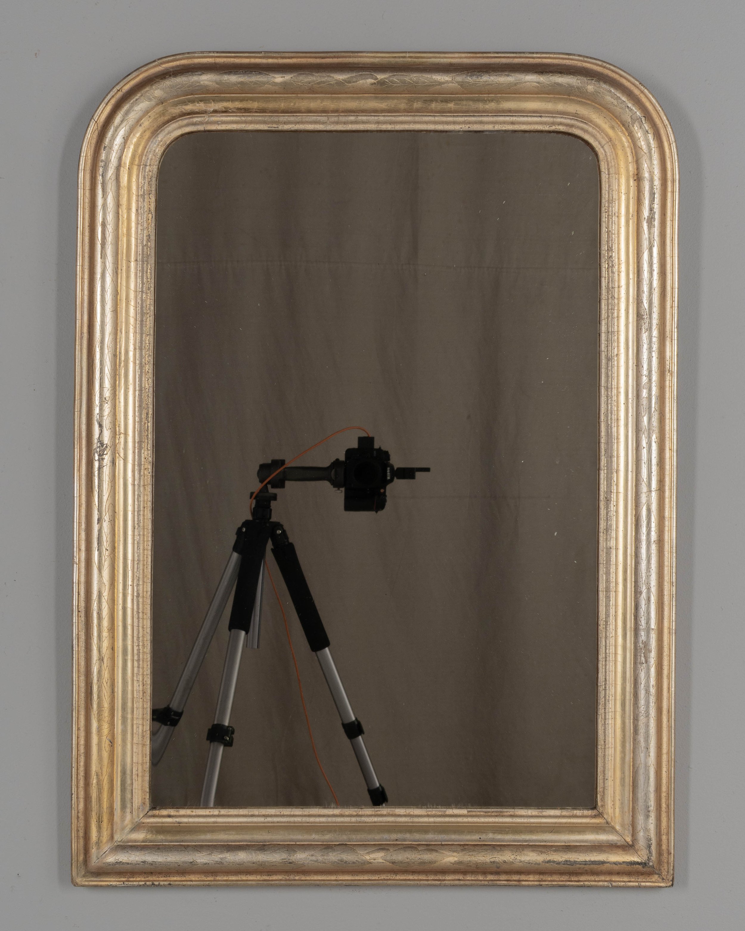 A French Louis Philippe style gilded mirror with curved top corners and incised floral decoration.