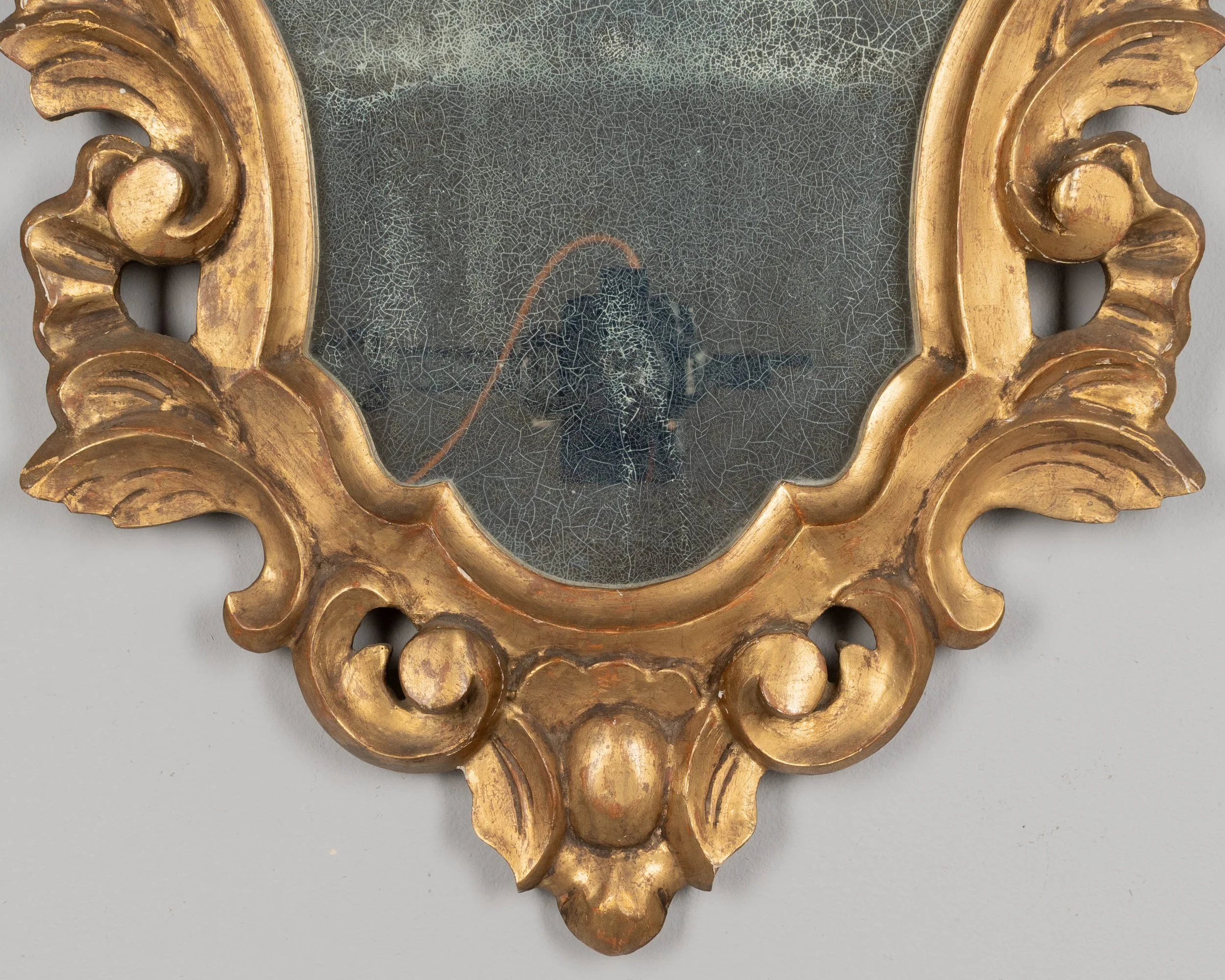 French Baroque style giltwood mirror with cartouche shape framed by undulating borders.