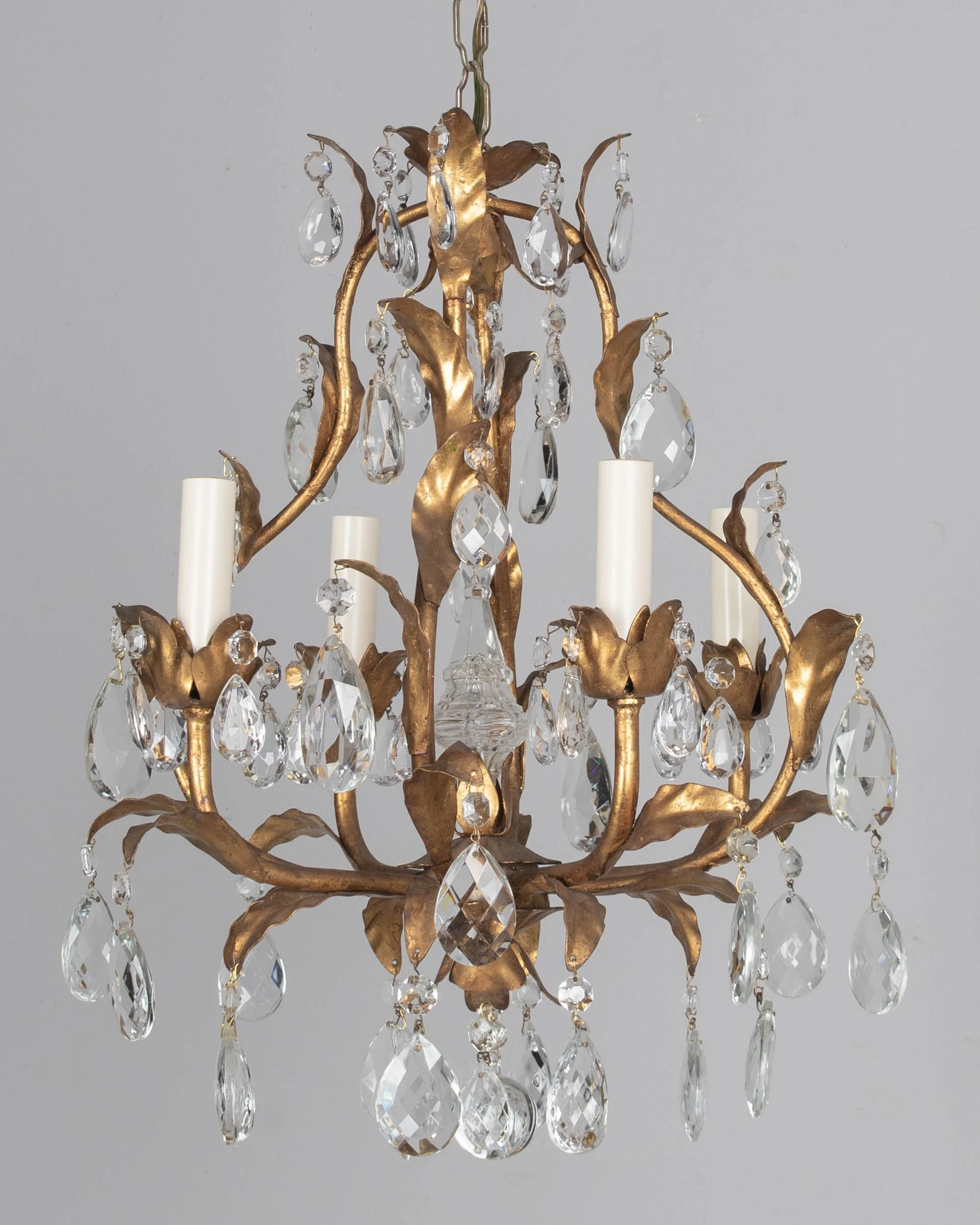 An Italian Hollywood Regency style four-light gilt metal chandelier with tôle leaves and crystal prisms.