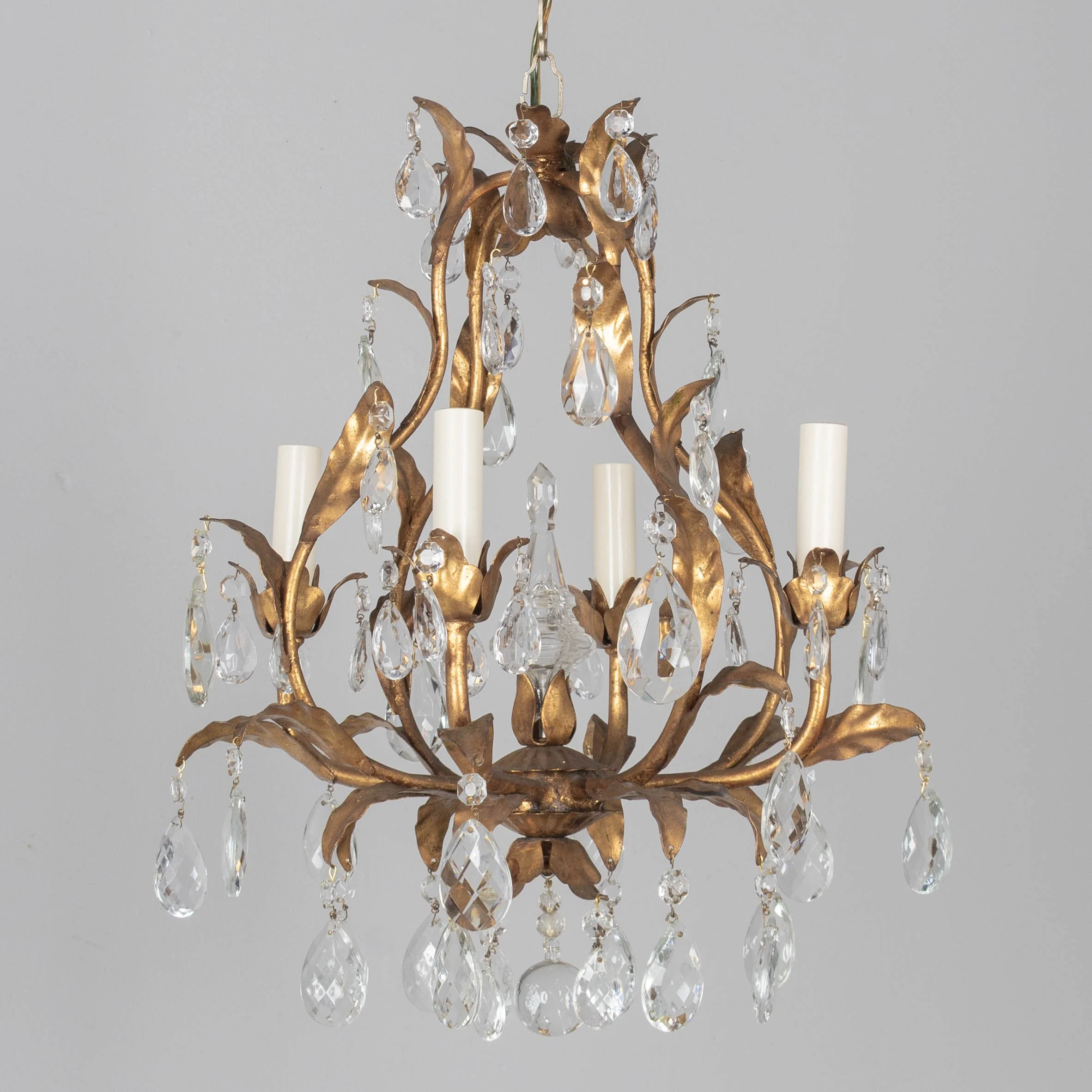 An Italian Hollywood Regency style four-light gilt metal chandelier with tôle leaves and crystal prisms.