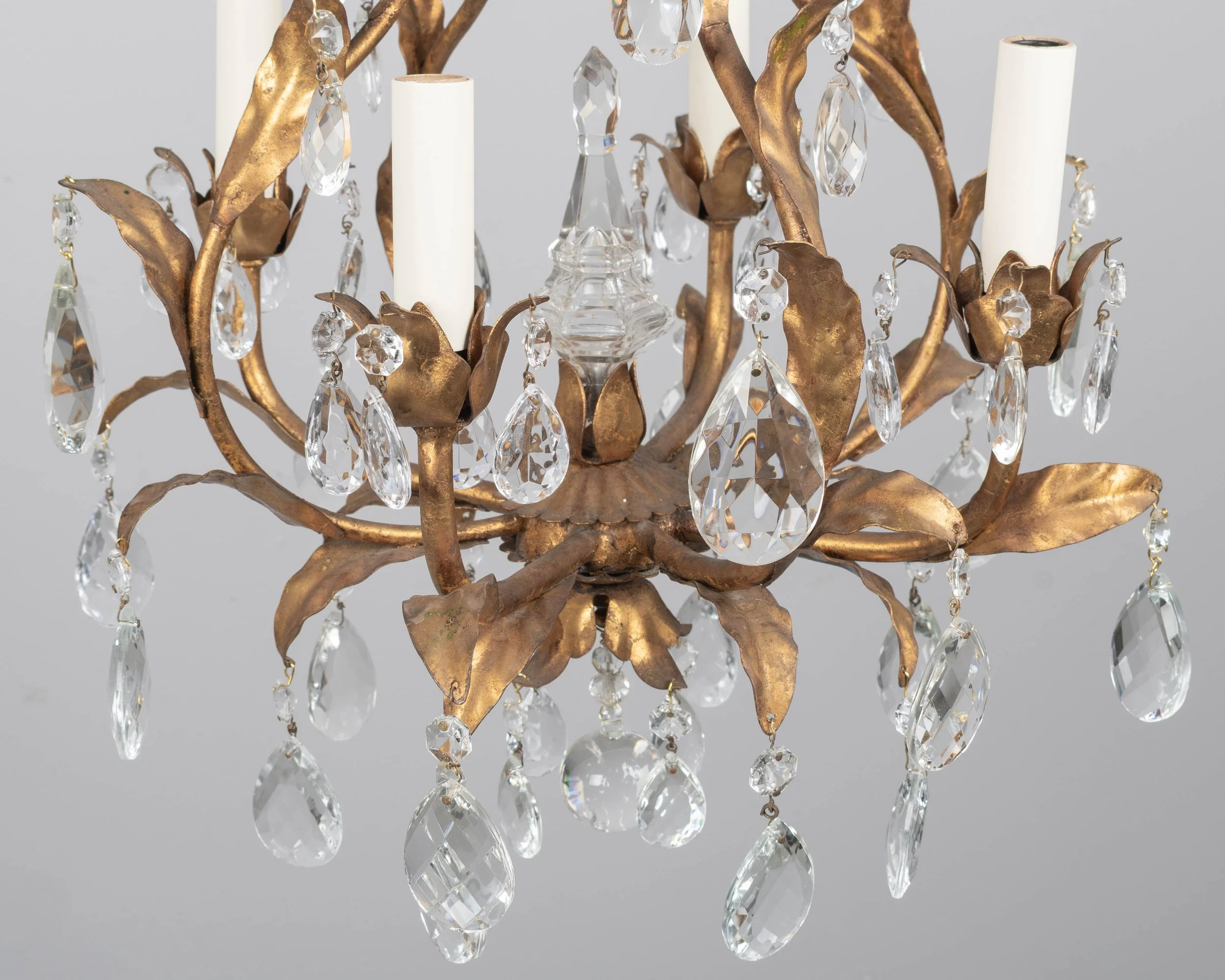 An Italian Hollywood Regency style four-light gilt metal chandelier with tôle leaves and crystal prisms.