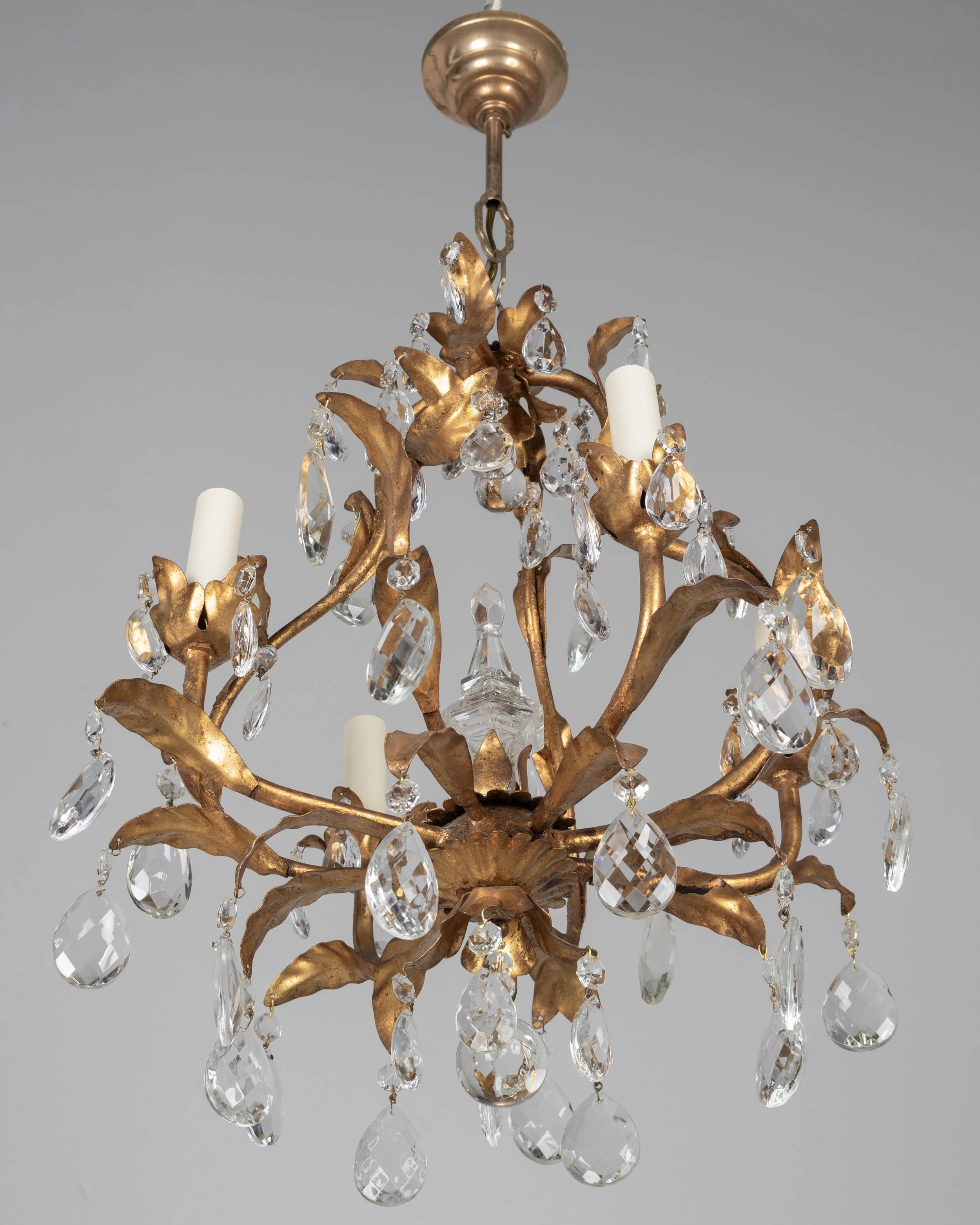 An Italian Hollywood Regency style four-light gilt metal chandelier with tôle leaves and crystal prisms.