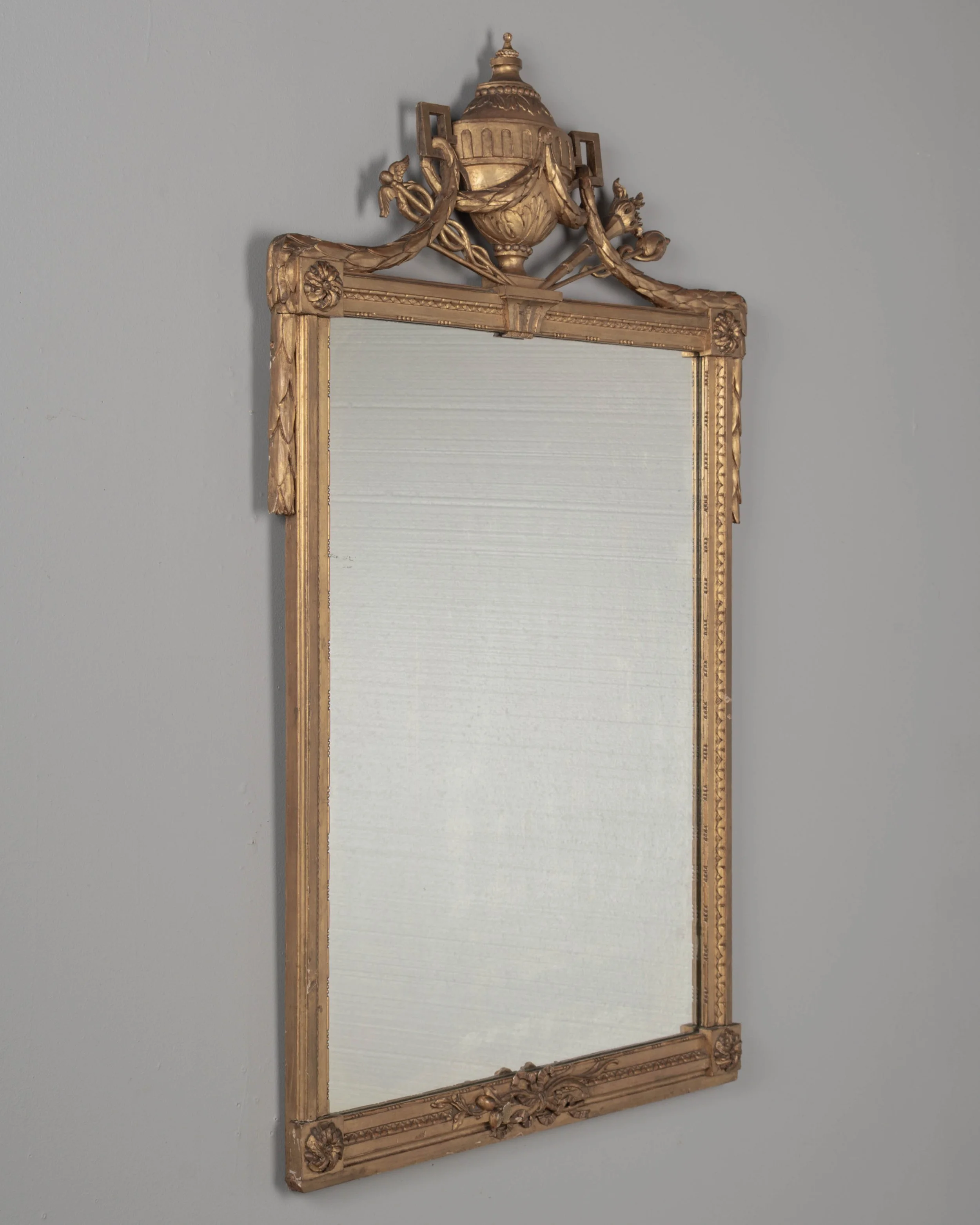 A Louis XVI style French giltwood mirror. Hand carved crest with large urn, torch, ribbons, and garlands.