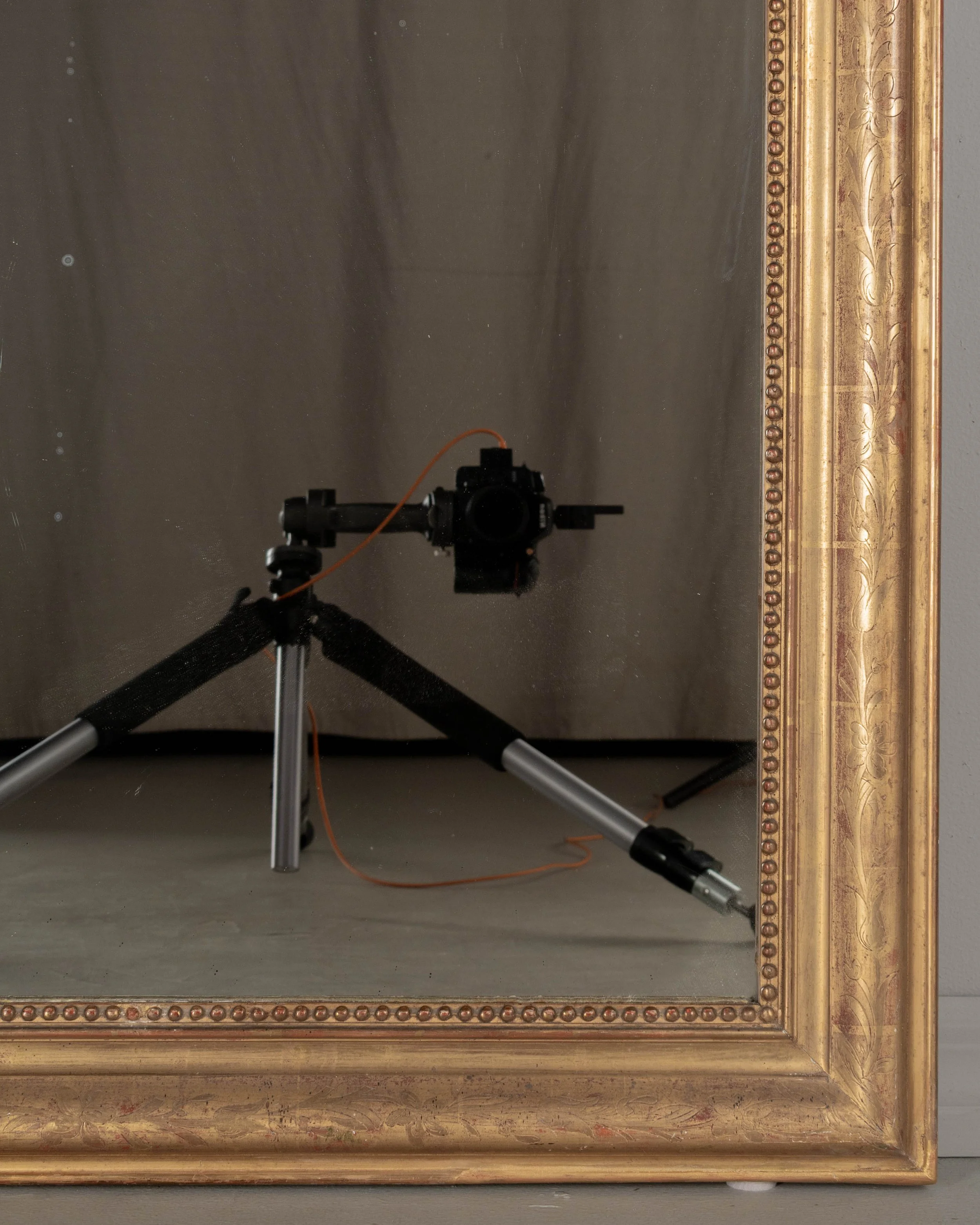 An early 20th century French Louis Philippe style gilded mirror with curved top corners, incised floral decoration and inner bead border.