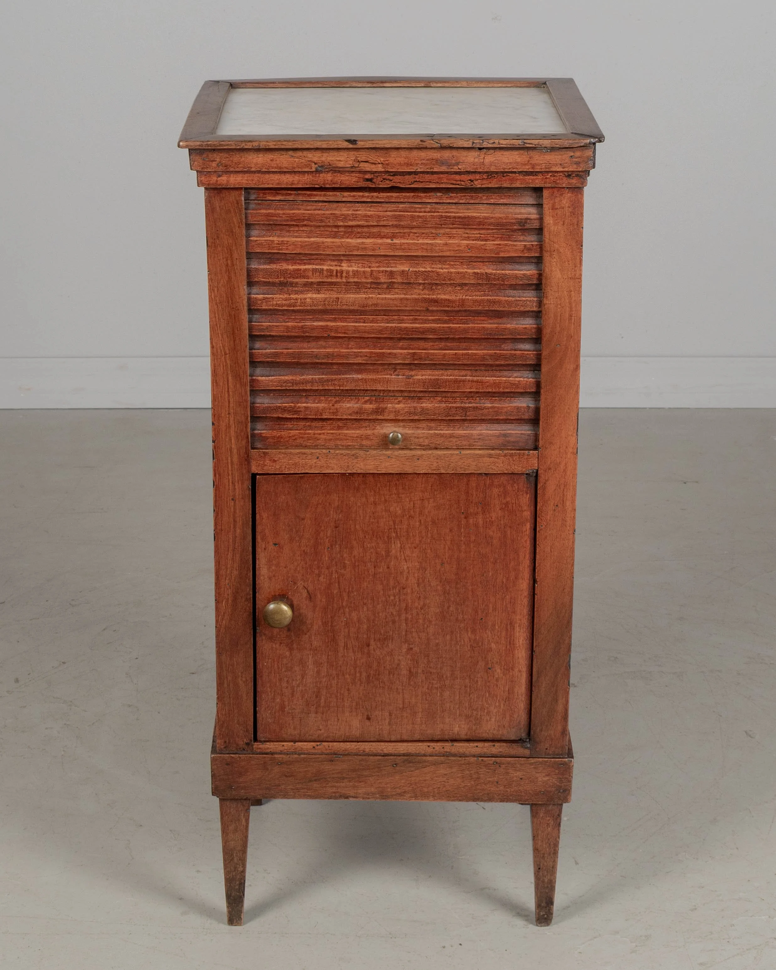 A 19th century French Country walnut side table, or nightstand, with a vertical tambour door above a cabinet door