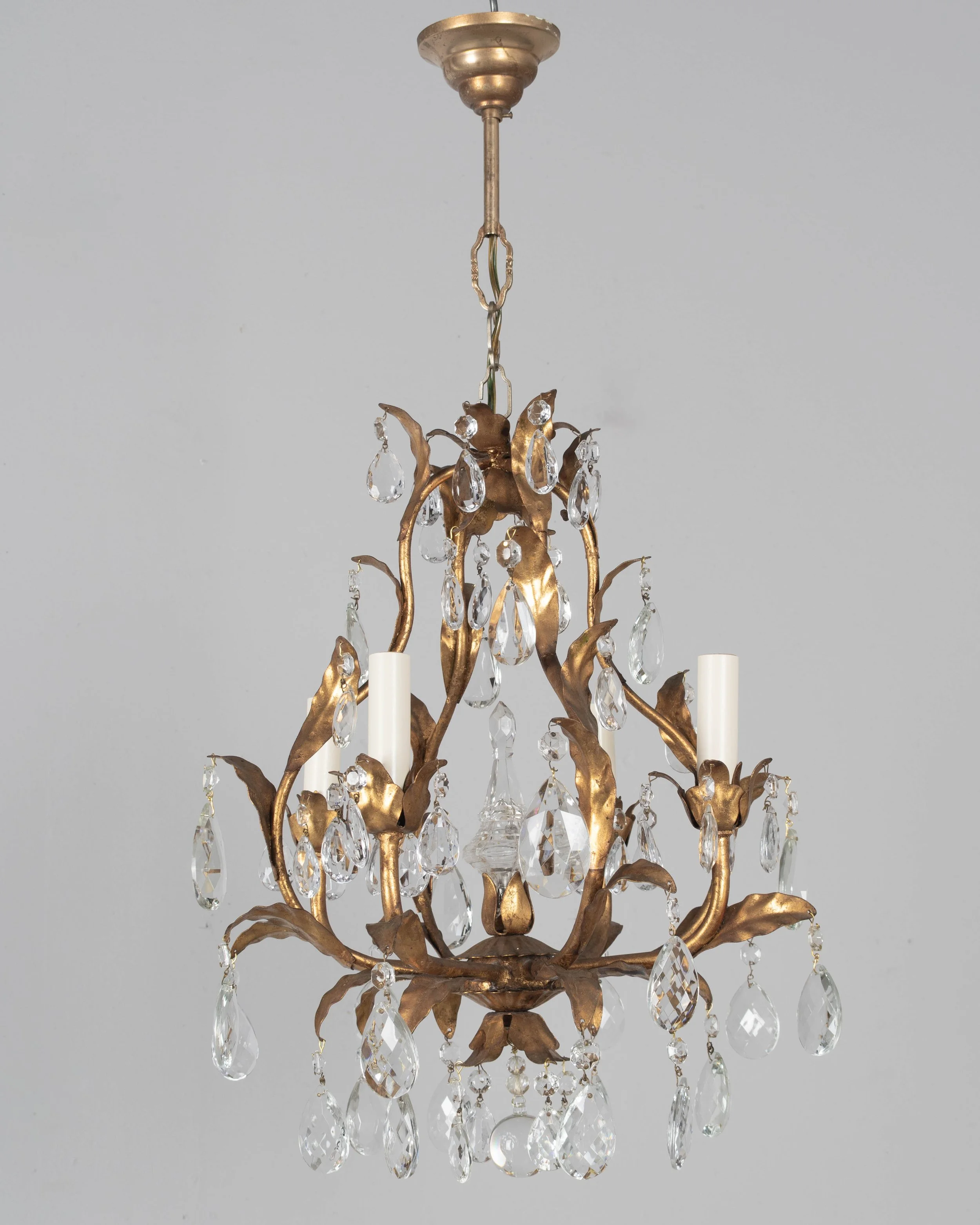 An Italian Hollywood Regency style four-light gilt metal chandelier with tôle leaves and crystal prisms.
