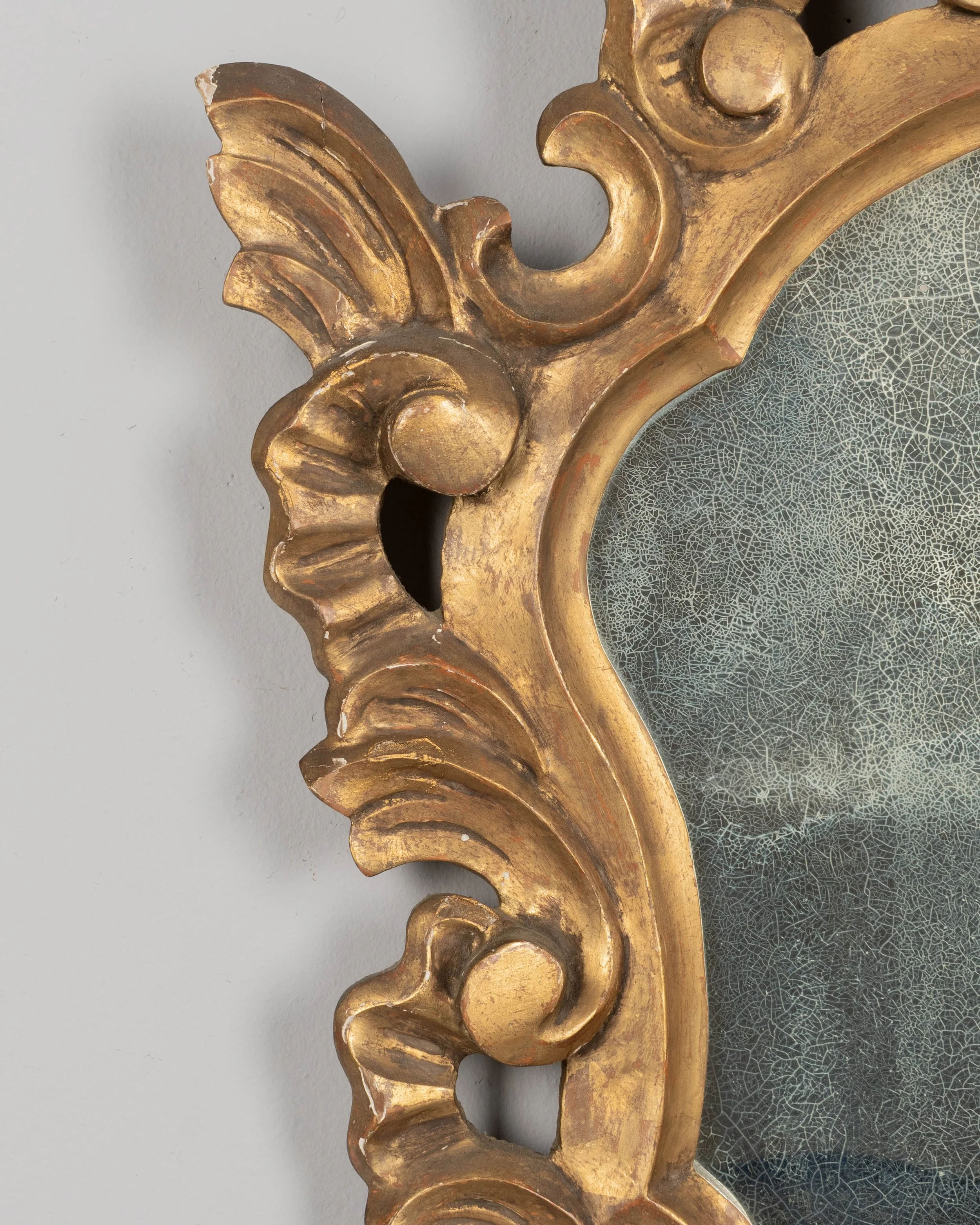 French Baroque style giltwood mirror with cartouche shape framed by undulating borders.