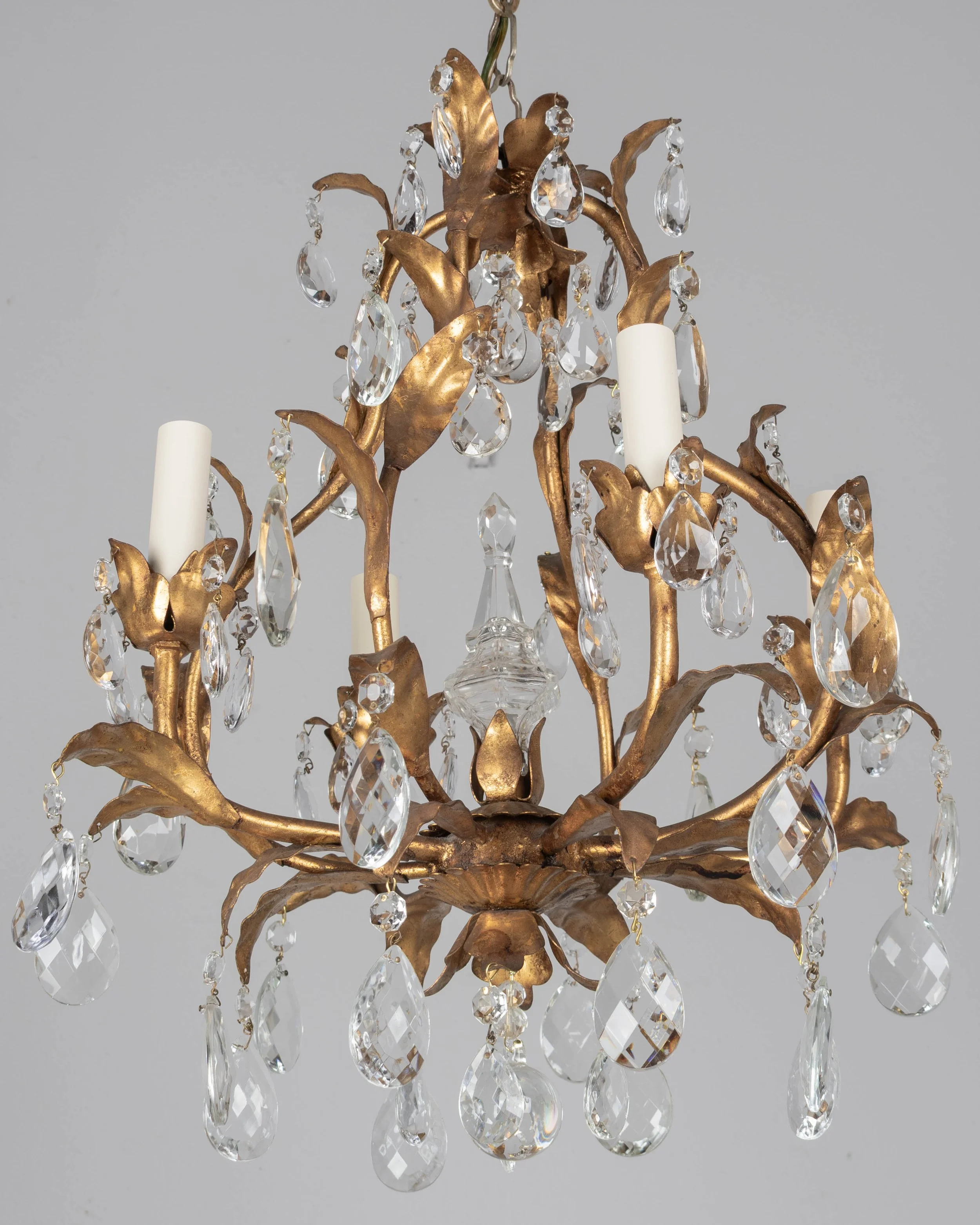 An Italian Hollywood Regency style four-light gilt metal chandelier with tôle leaves and crystal prisms.