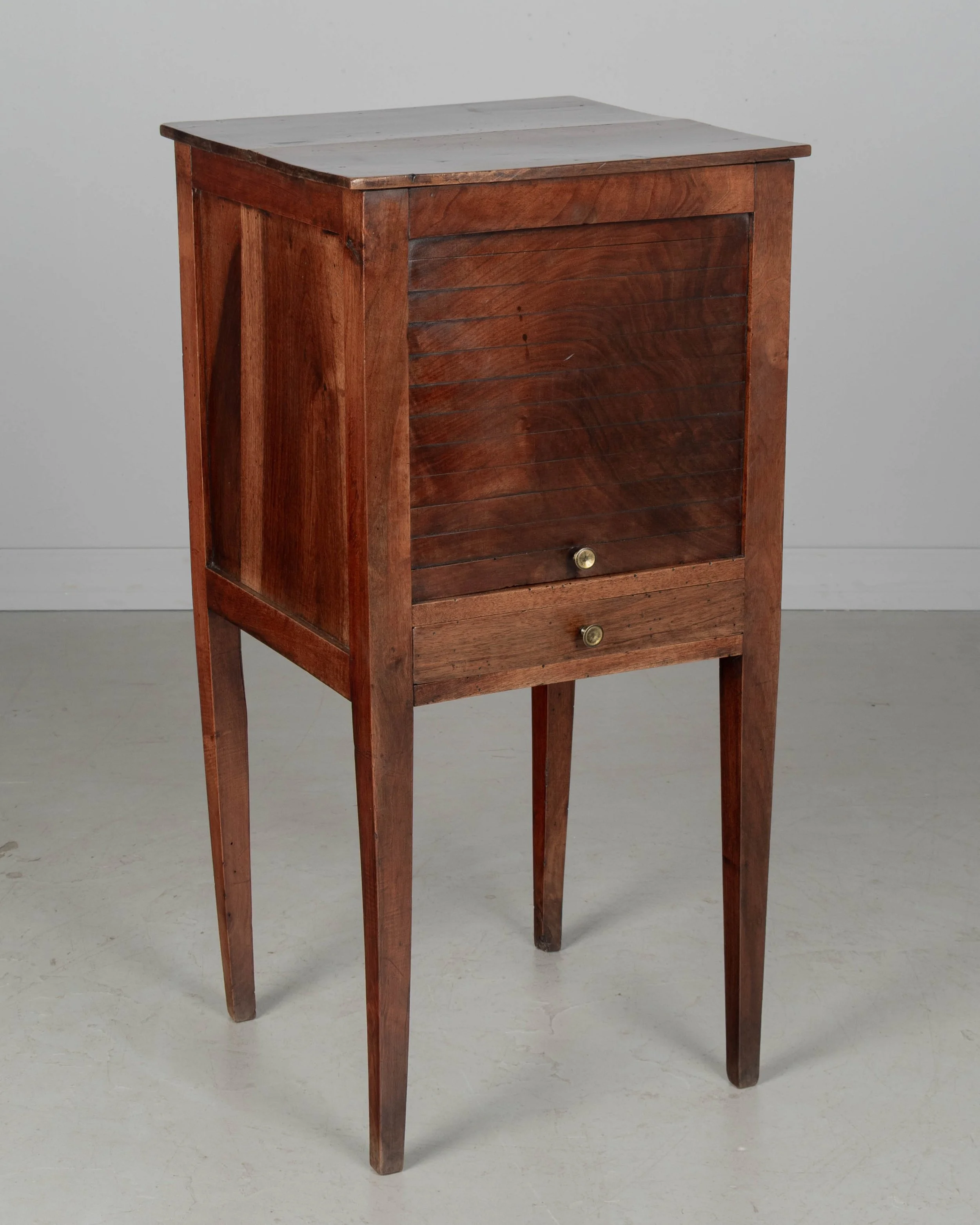 A 19th century French Country walnut side table, or nightstand, with a vertical tambour door above a slim dovetailed drawer