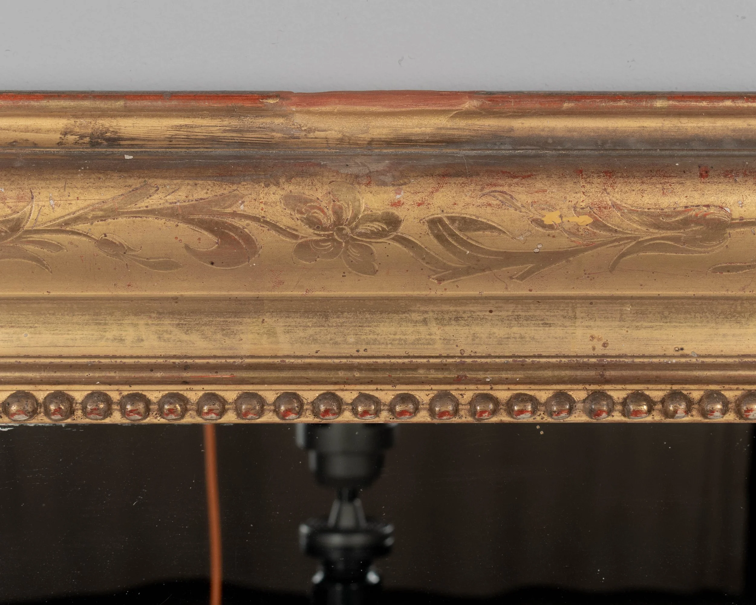 An early 20th century French Louis Philippe style gilded mirror with curved top corners, incised floral decoration and inner bead border.