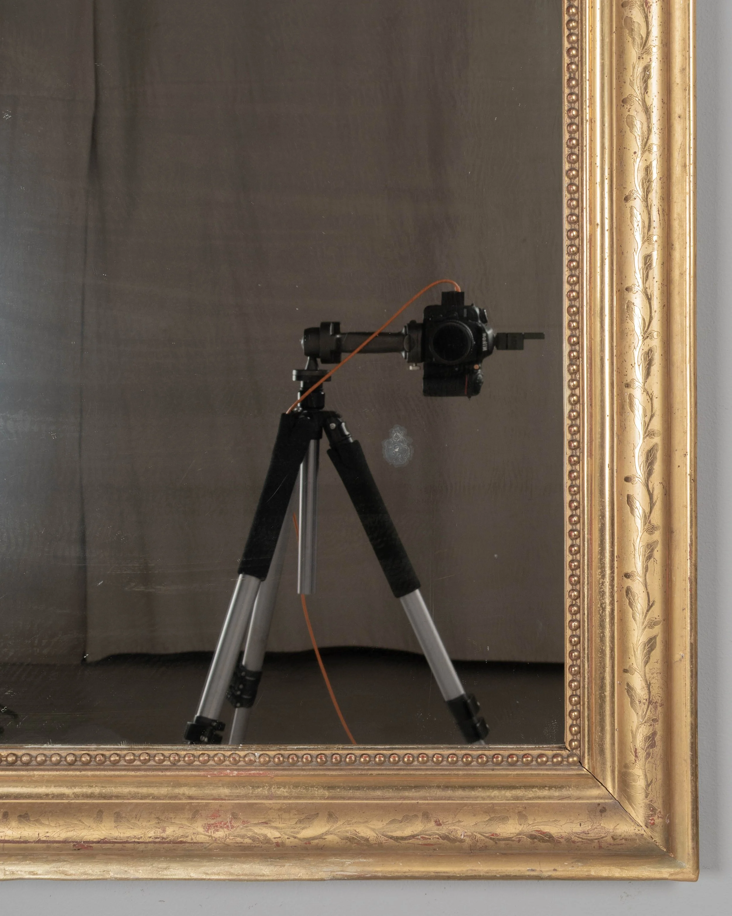 An early 20th century French Louis Philippe style gilded mirror with curved top corners, incised floral decoration and inner bead border.