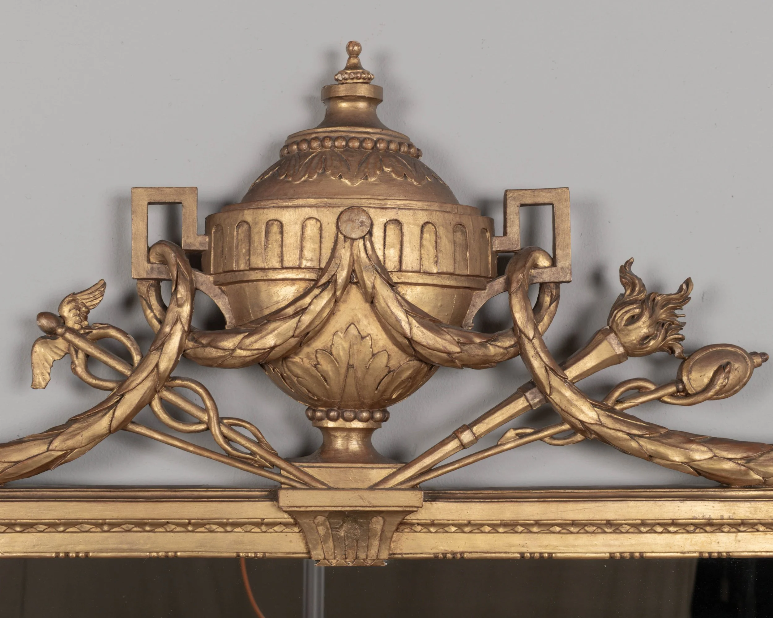 A Louis XVI style French giltwood mirror. Hand carved crest with large urn, torch, ribbons, and garlands.