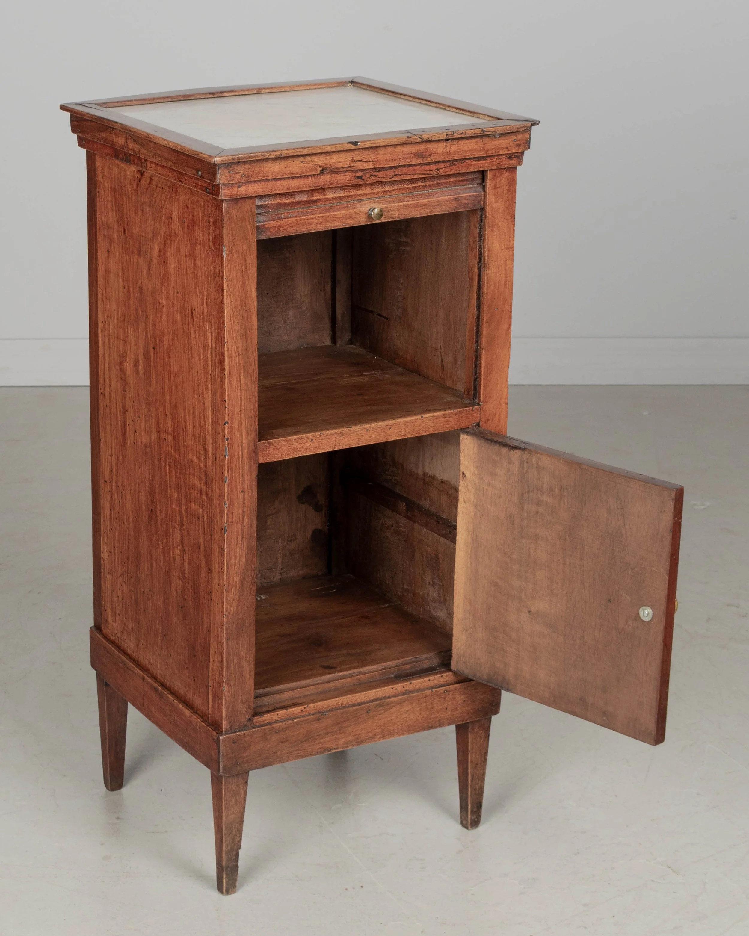 A 19th century French Country walnut side table, or nightstand, with a vertical tambour door above a cabinet door