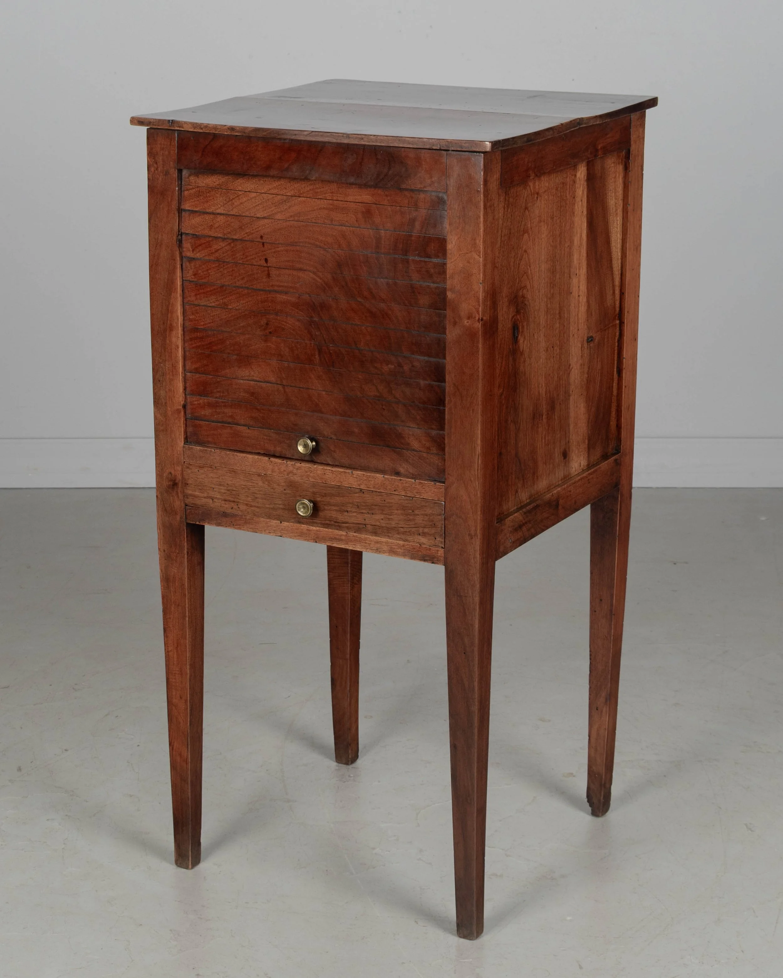 A 19th century French Country walnut side table, or nightstand, with a vertical tambour door above a slim dovetailed drawer