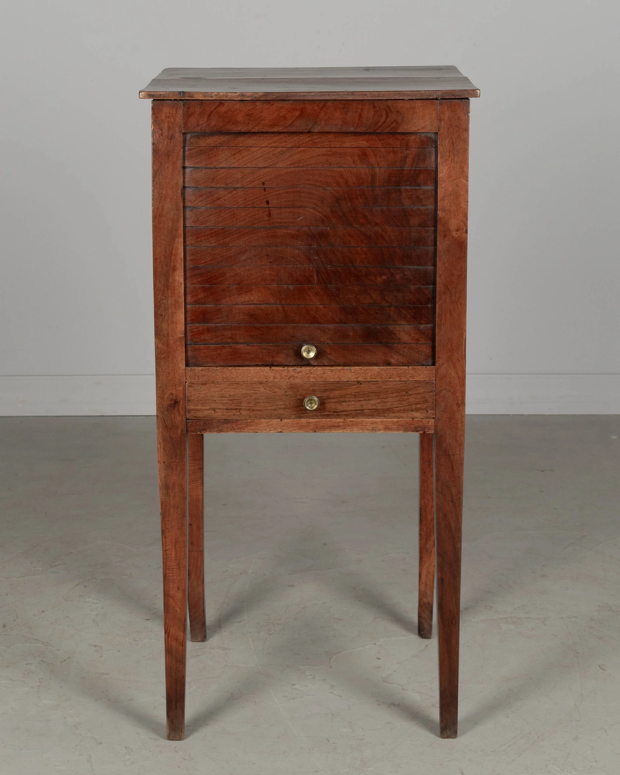 A 19th century French Country walnut side table, or nightstand, with a vertical tambour door above a slim dovetailed drawer