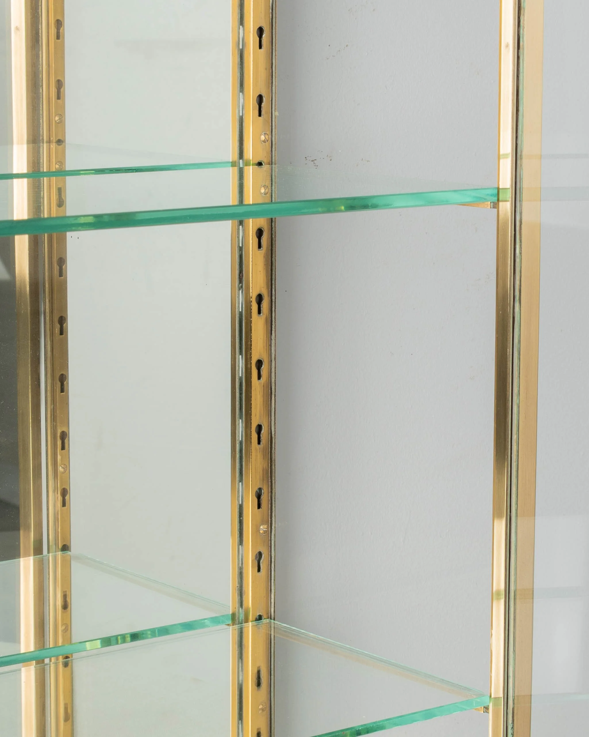 A French Art Deco hanging wall vitrine with solid brass frame, mirrored back and glass panes.