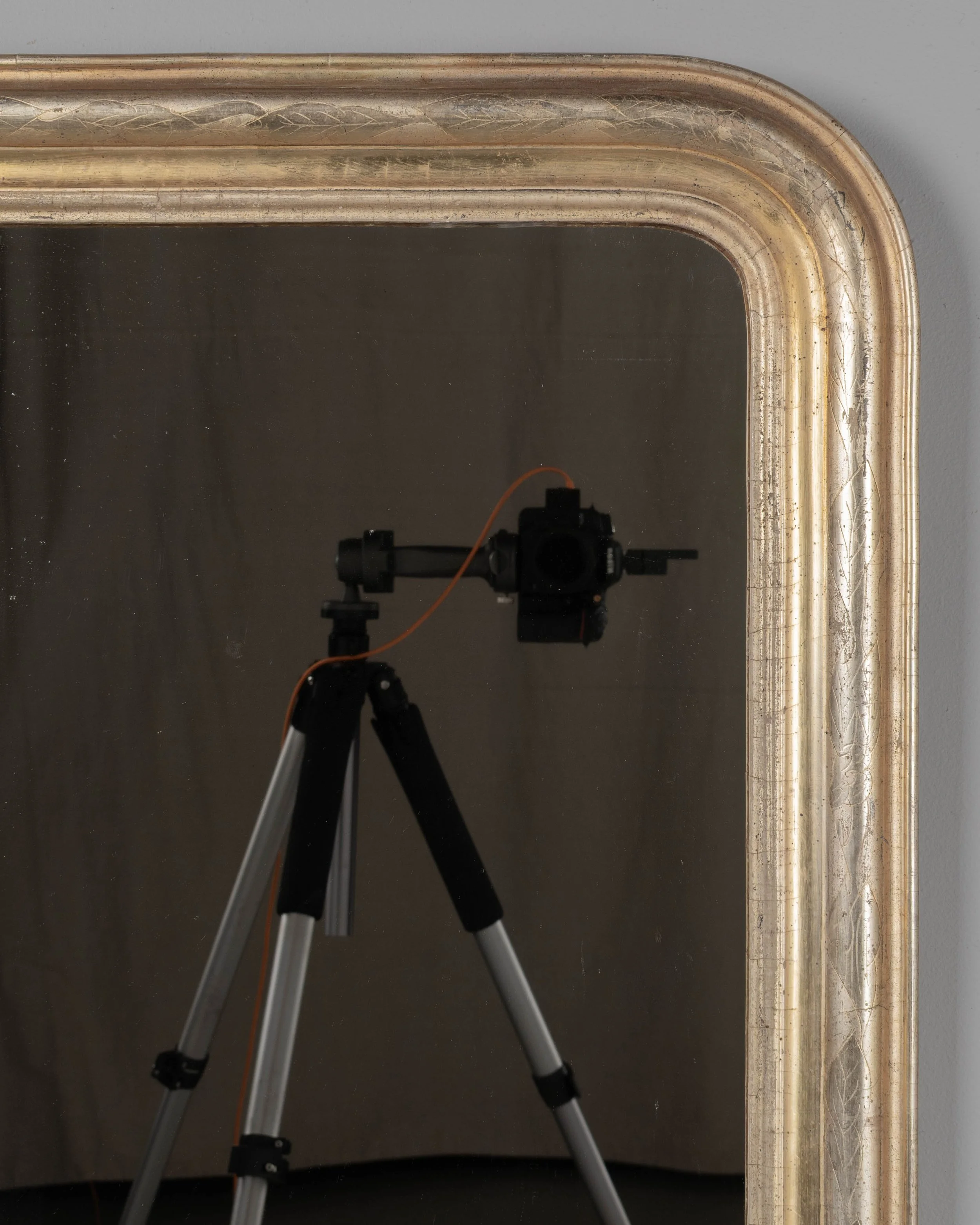 A French Louis Philippe style gilded mirror with curved top corners and incised floral decoration.